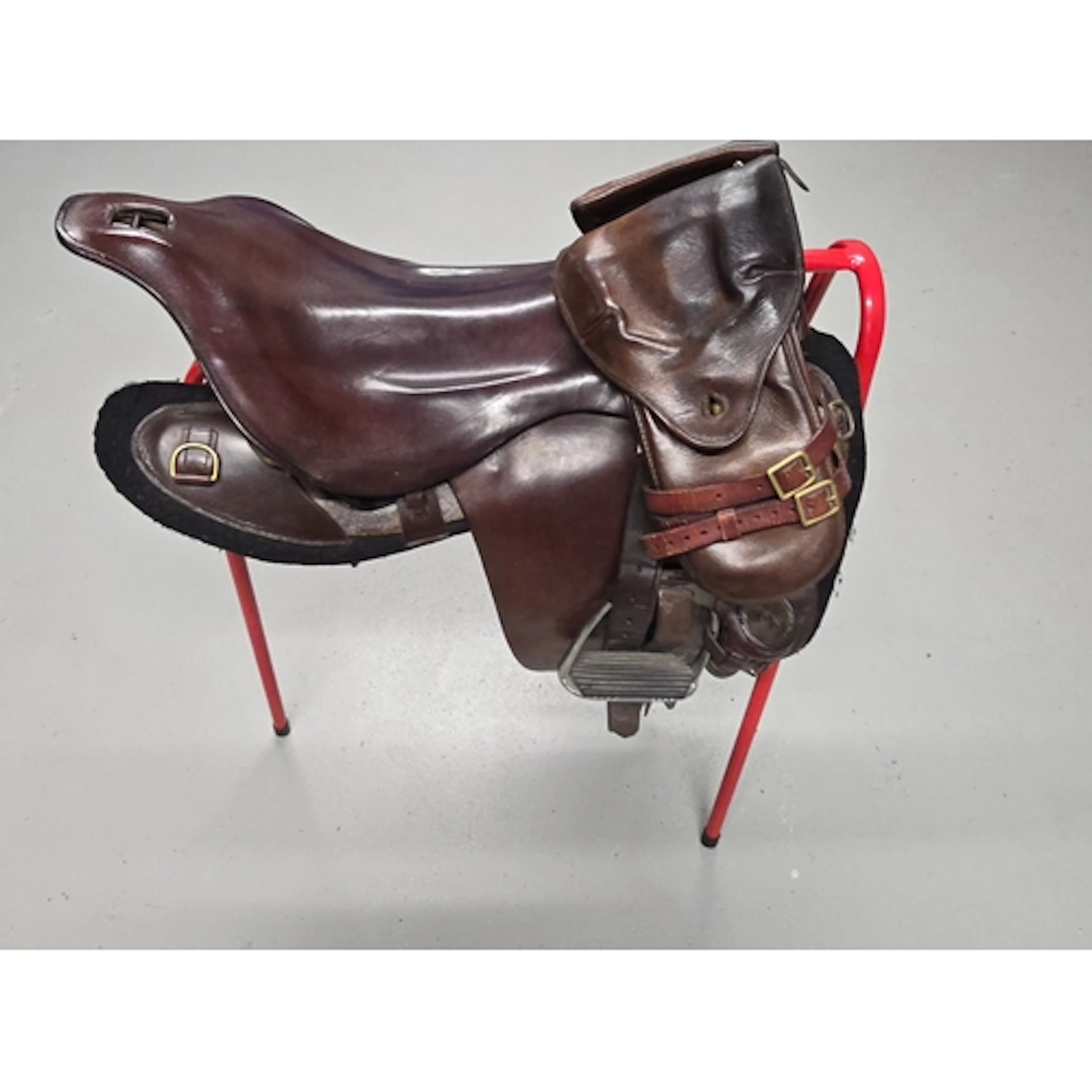 A brown leather saddle of military type with brass buckles, ...