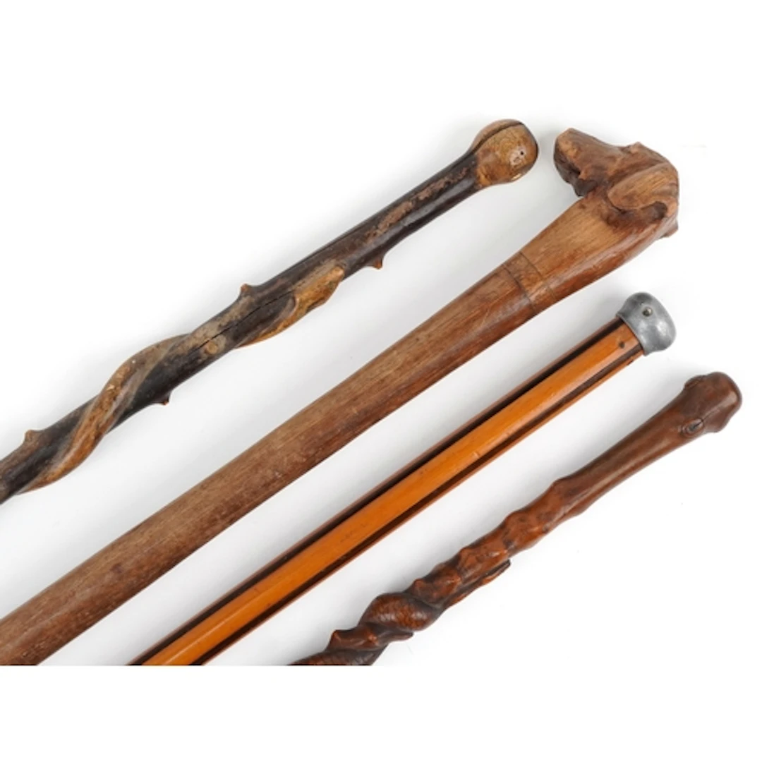 Four wooden walking sticks, one carved with a serpent, the l...