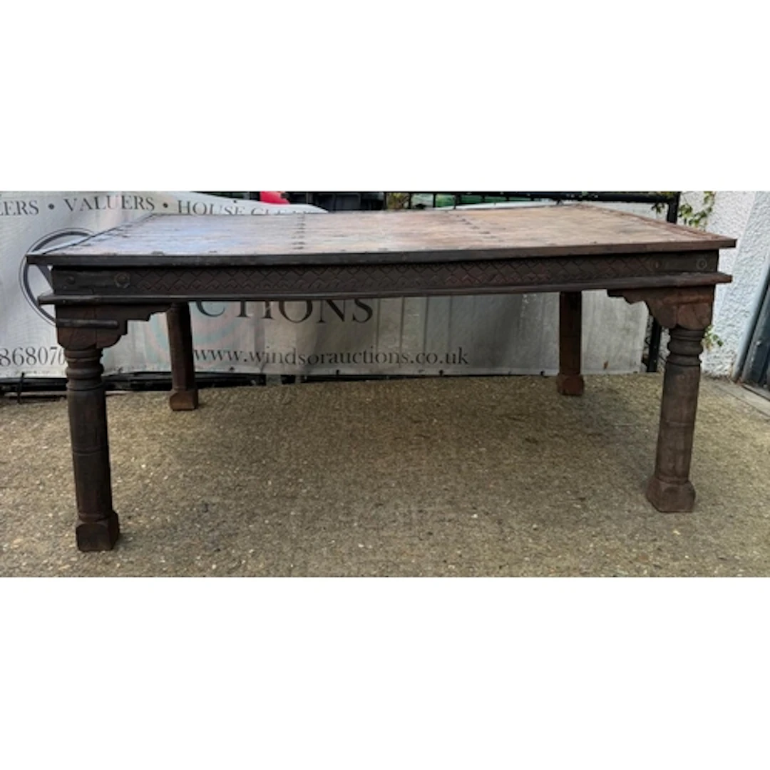 An Indian hardwood dining table with turned legs and cast ir...