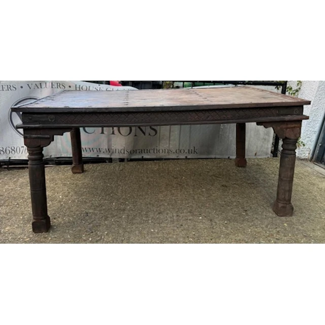 An Indian hardwood dining table with turned legs and cast ir...