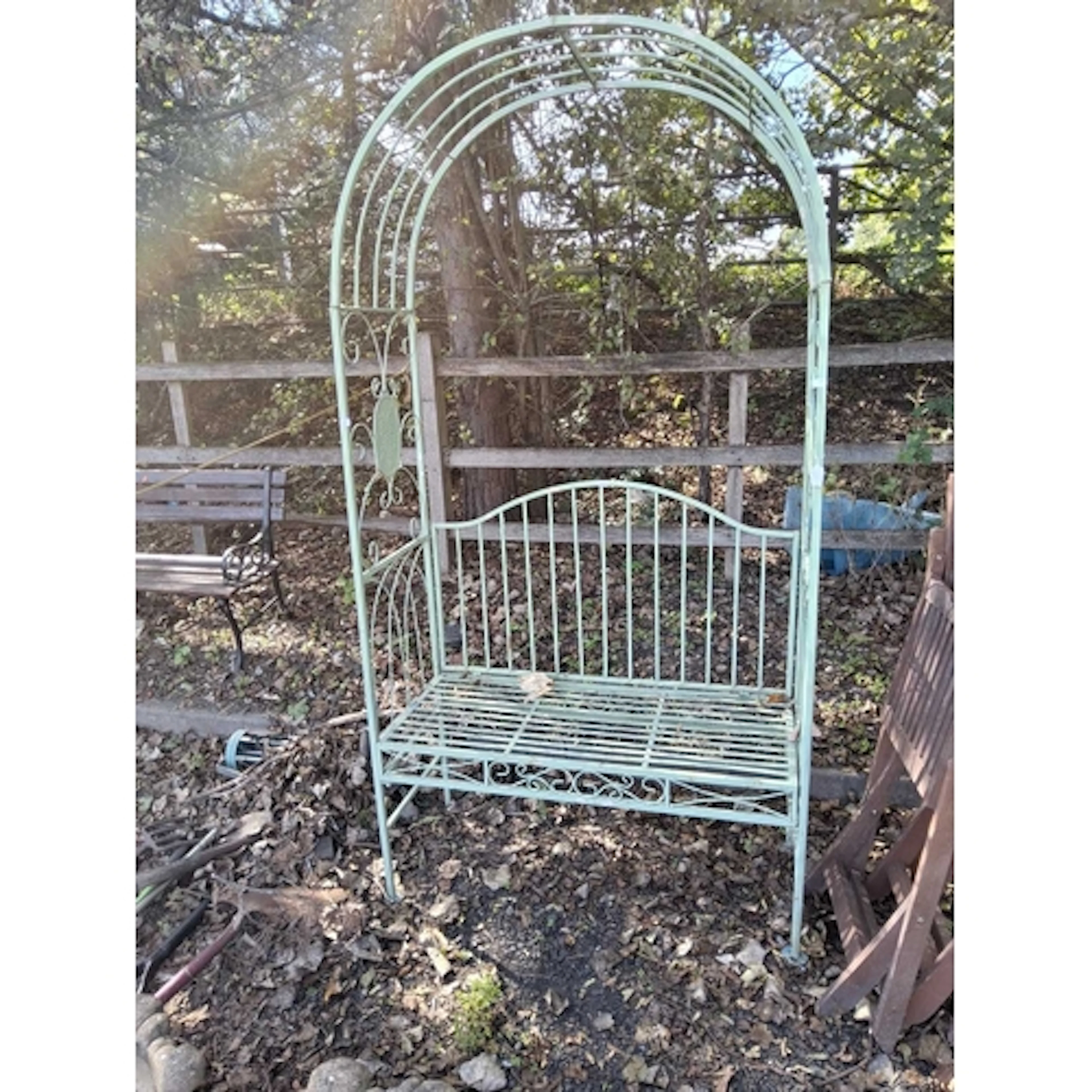 A MODERN METAL GARDEN ARBOUR with an arched top and seat bel...
