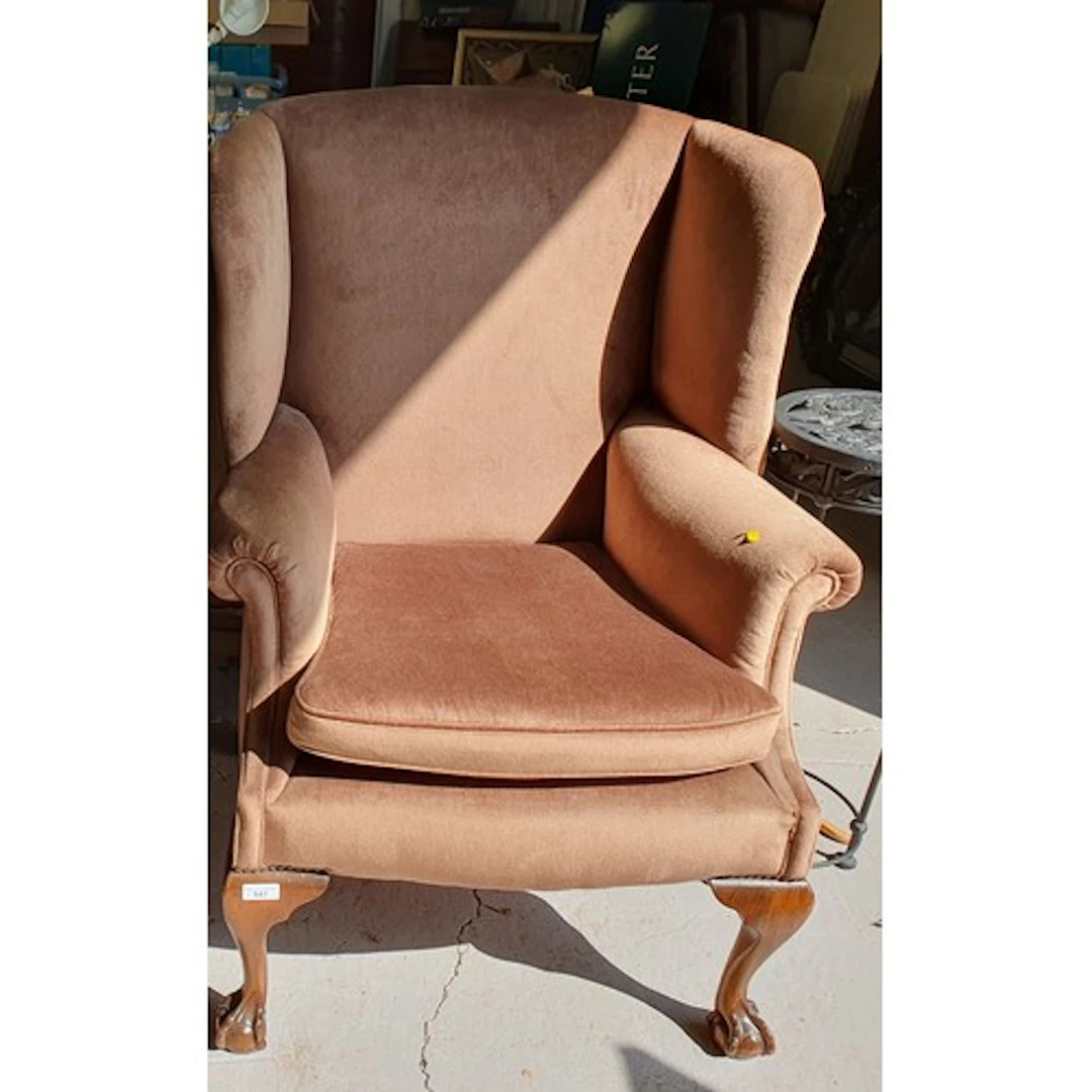 A large brown upholstered wingback Armchair raised on cabrio...