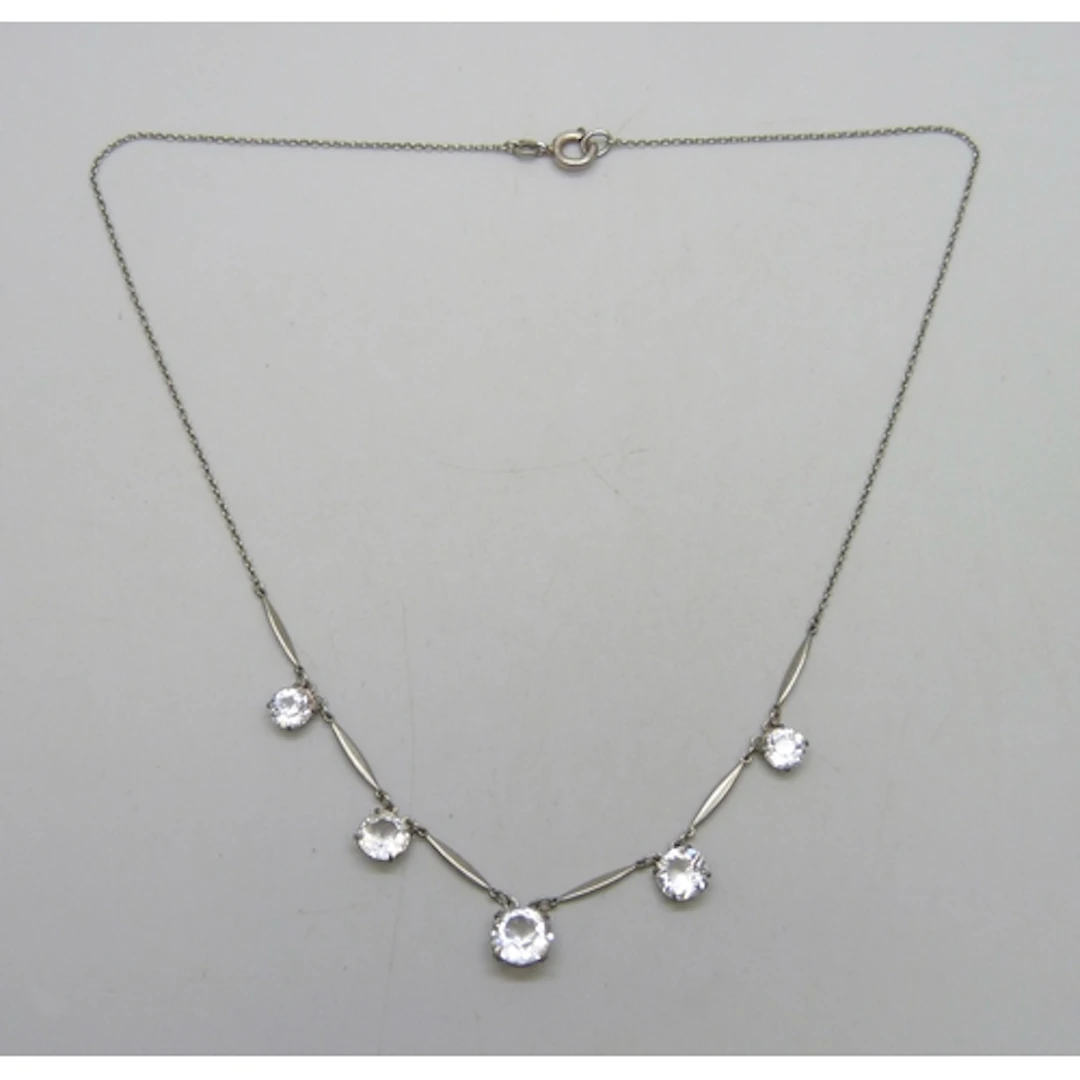 An Art Deco riviere drop necklace set with white paste stone...