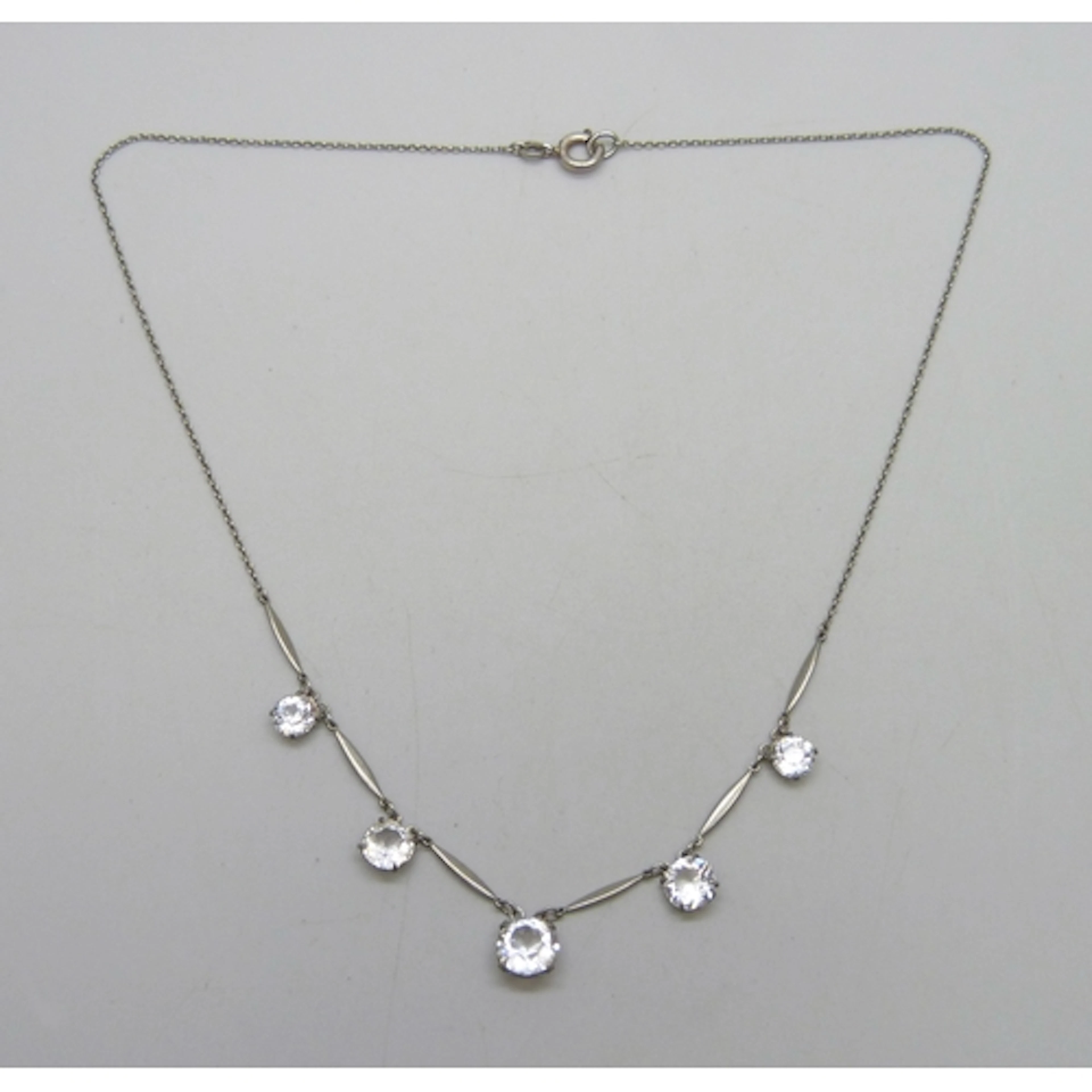 An Art Deco riviere drop necklace set with white paste stone...