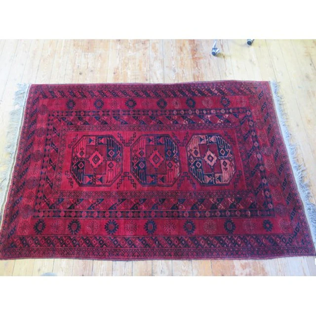 An Afghan rug, the wine red field with single row of three q...