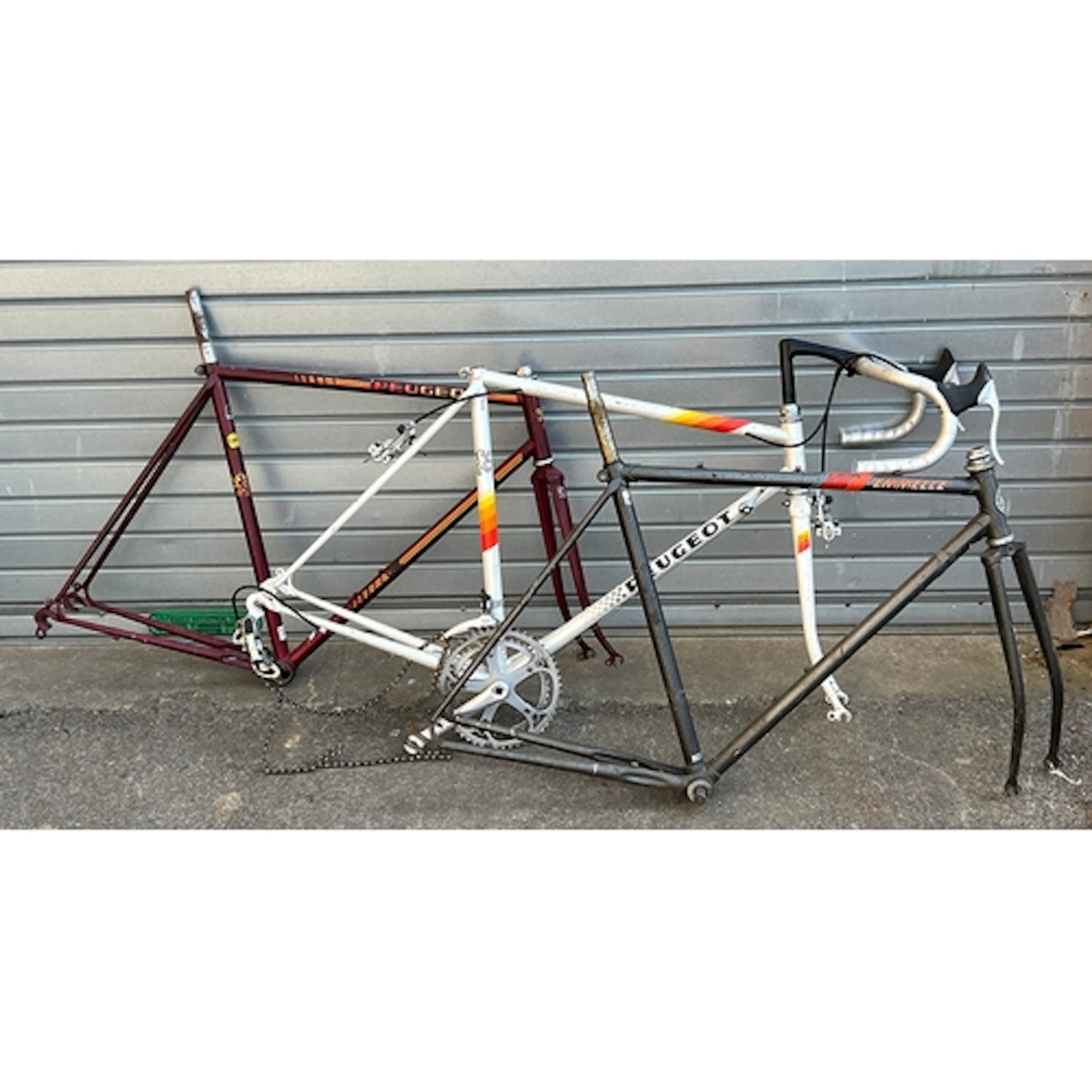 Three vintage steel road bike frames: two Peugeot, and one E...