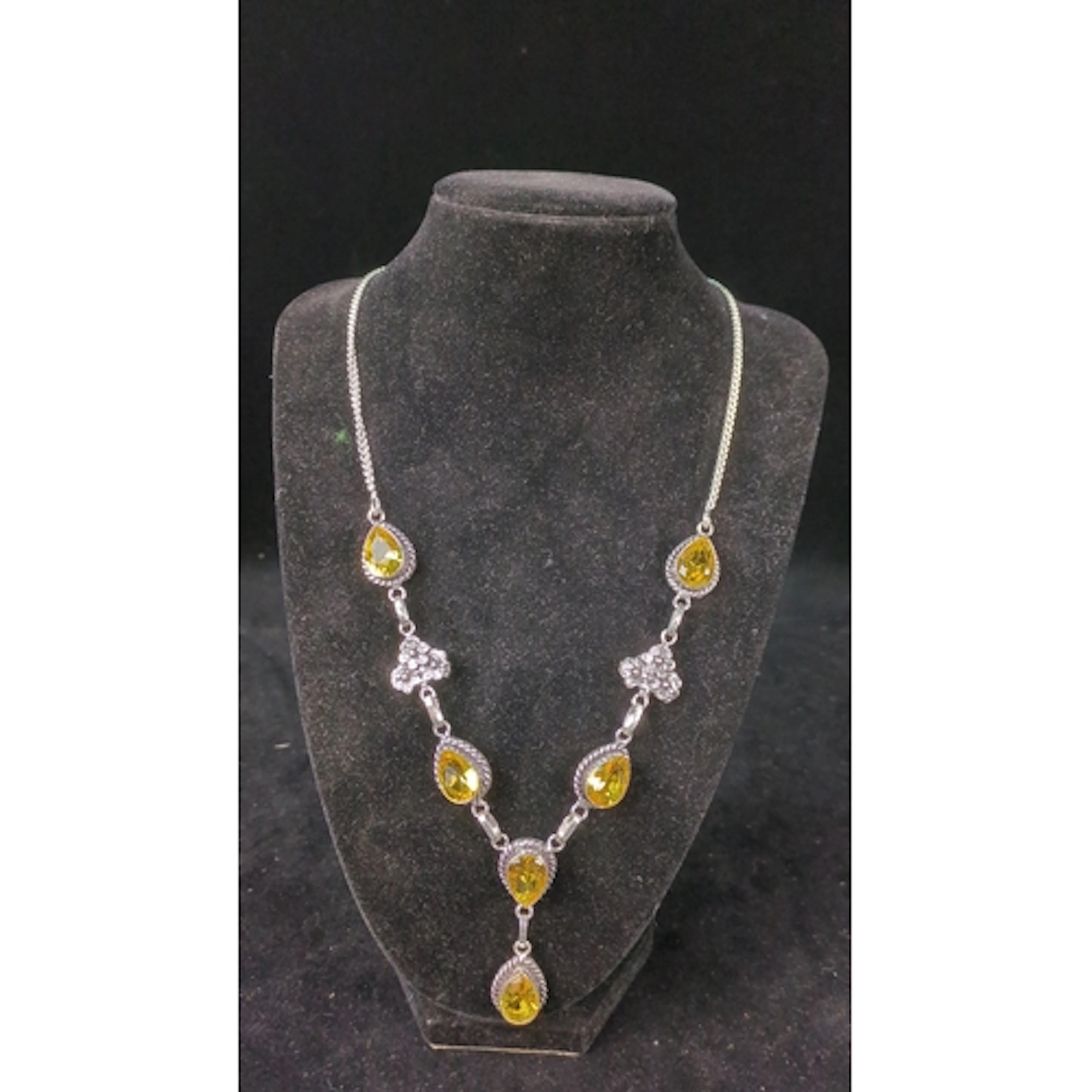 Silver necklace with faceted pear-shaped yellow stones in ro...