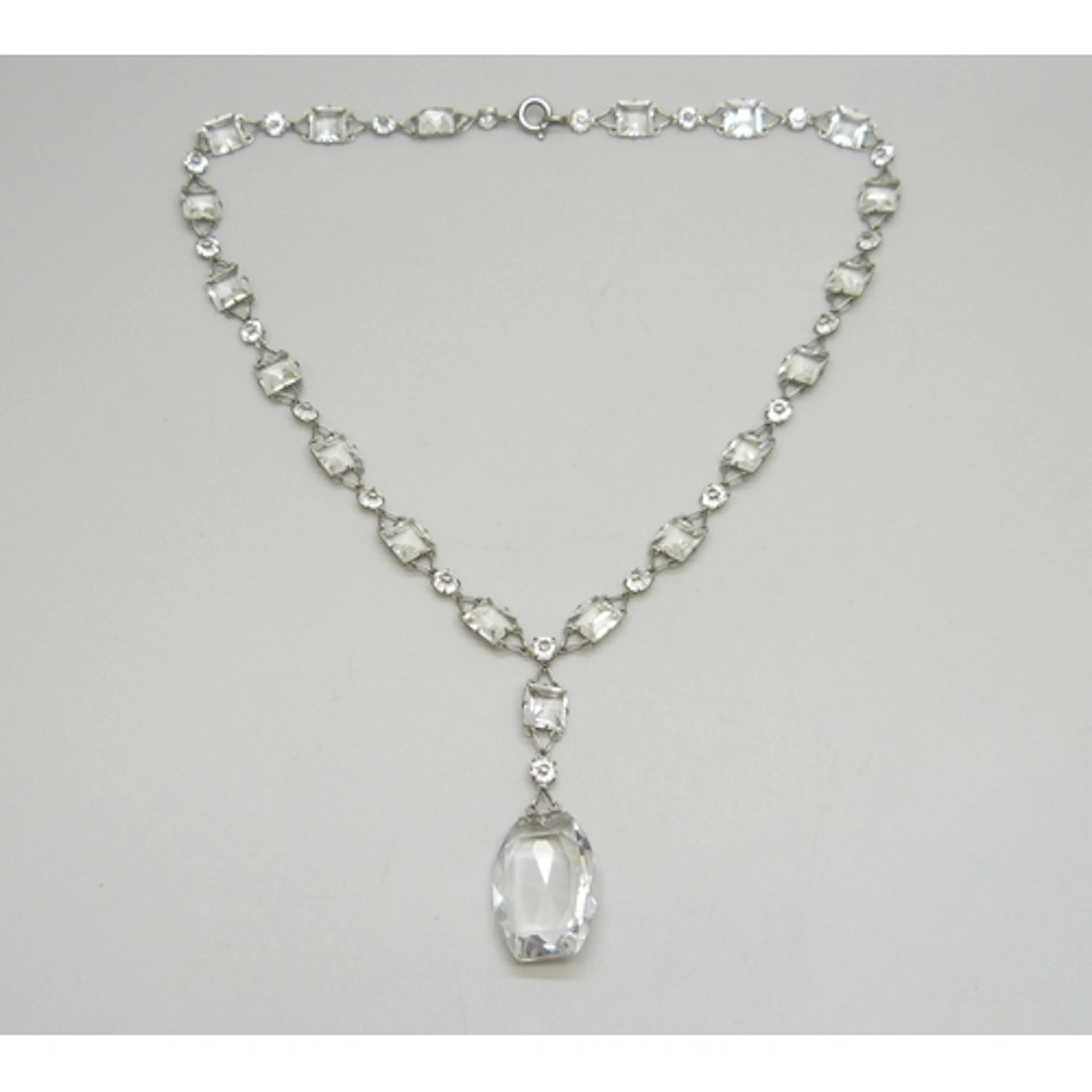A 1920s Art Deco platinon and white paste stone riviere drop...