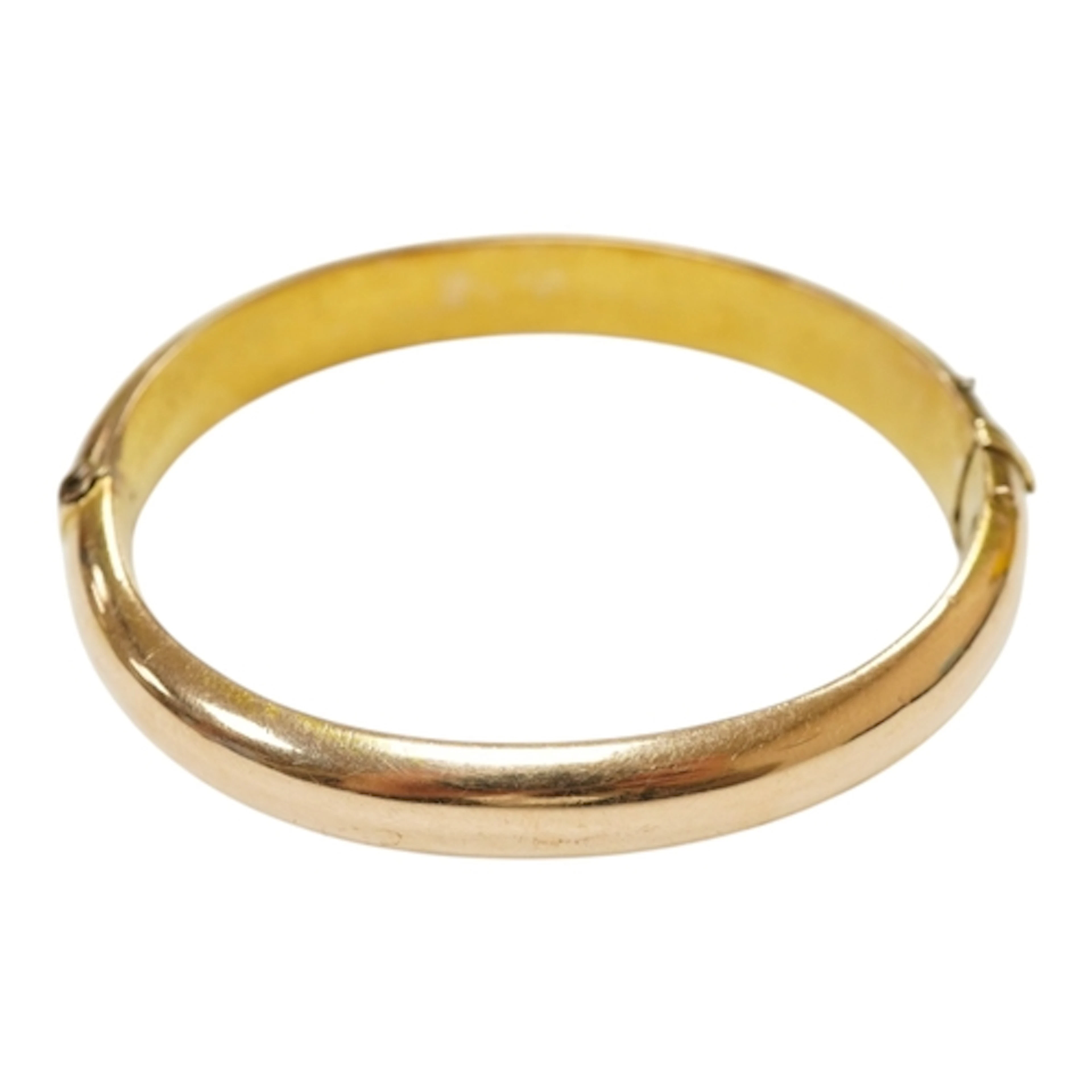 A late Victorian yellow metal hinged bangle, with engraved i...