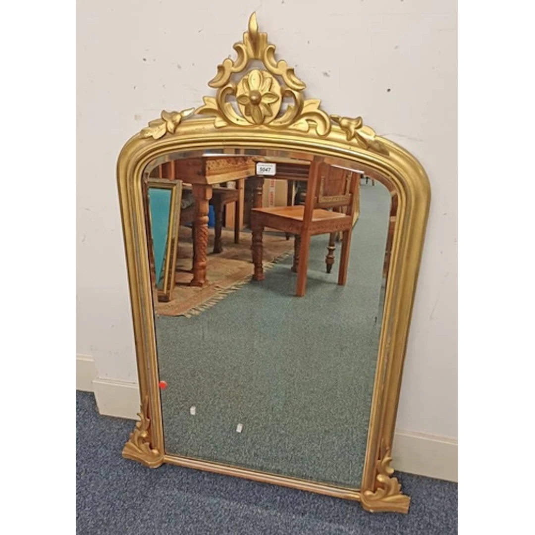 GILT FRAMED OVERMANTLE MIRROR SURMOUNTED BY CARVED FLORAL FI...