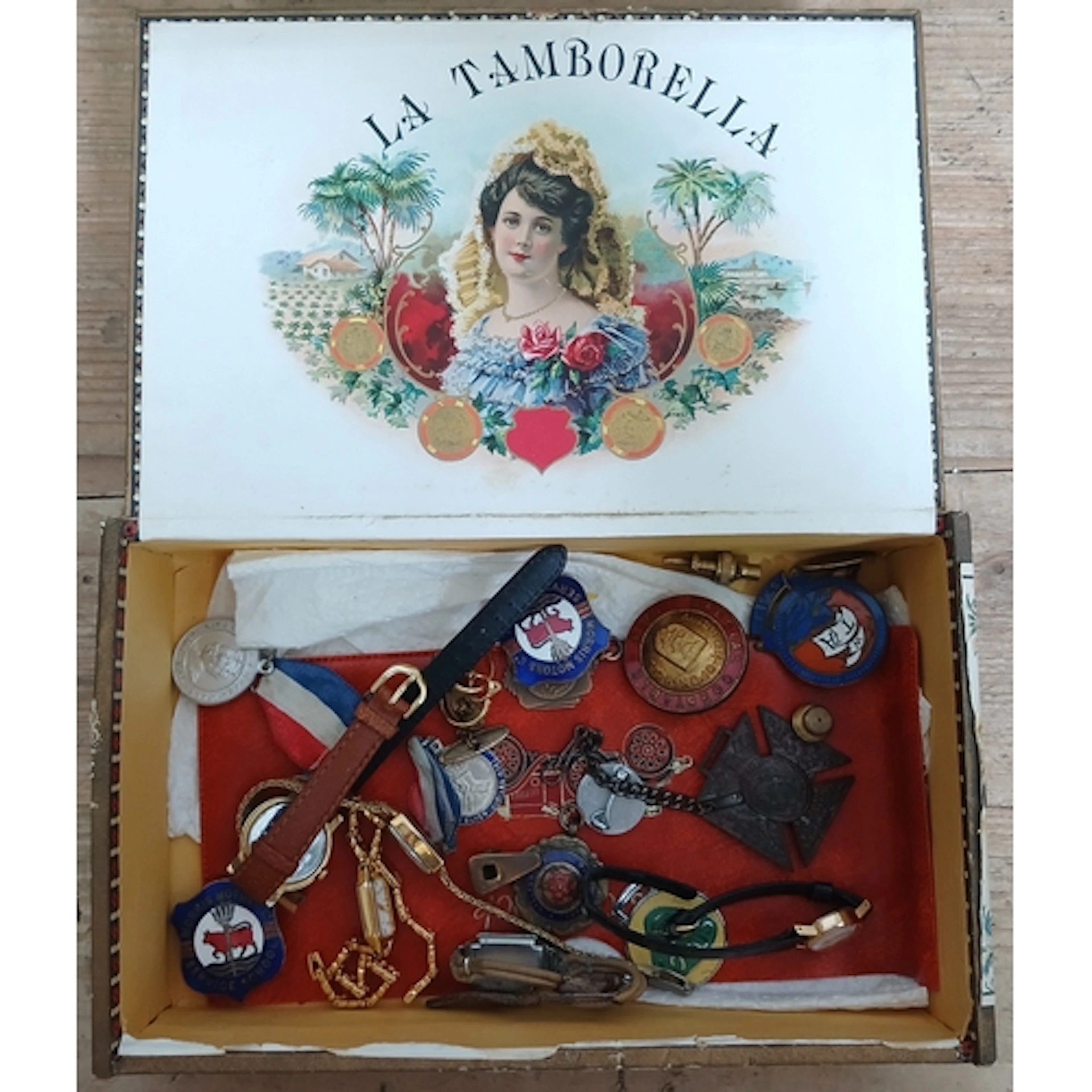 A cigar box of assorted collectables including badges etc.