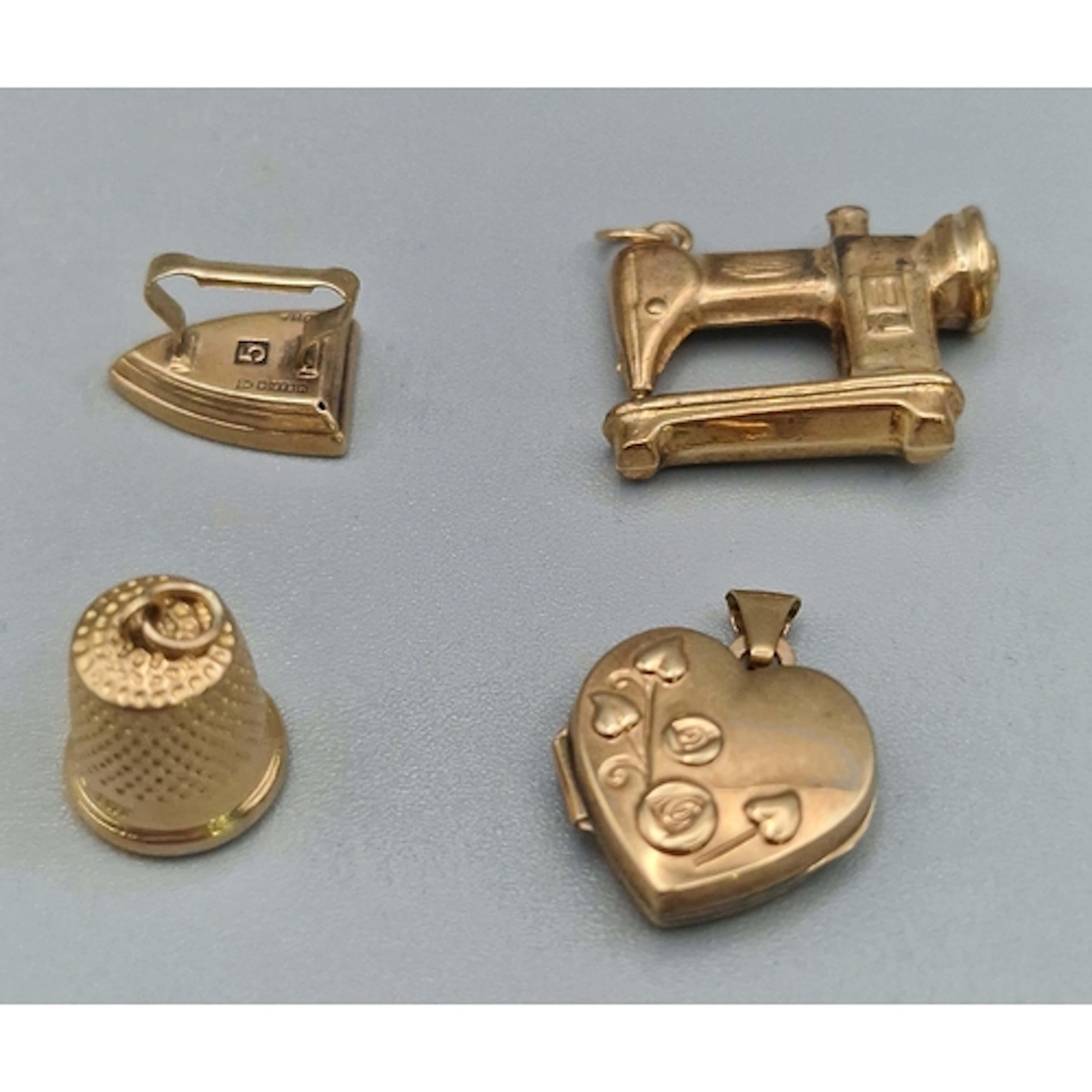 Three 9ct gold charms in the form of an iron, sewing machine...
