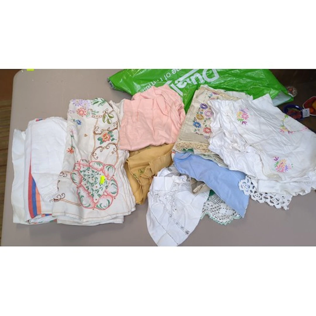 A quantity of embroidered table linens in white and pastel-c...