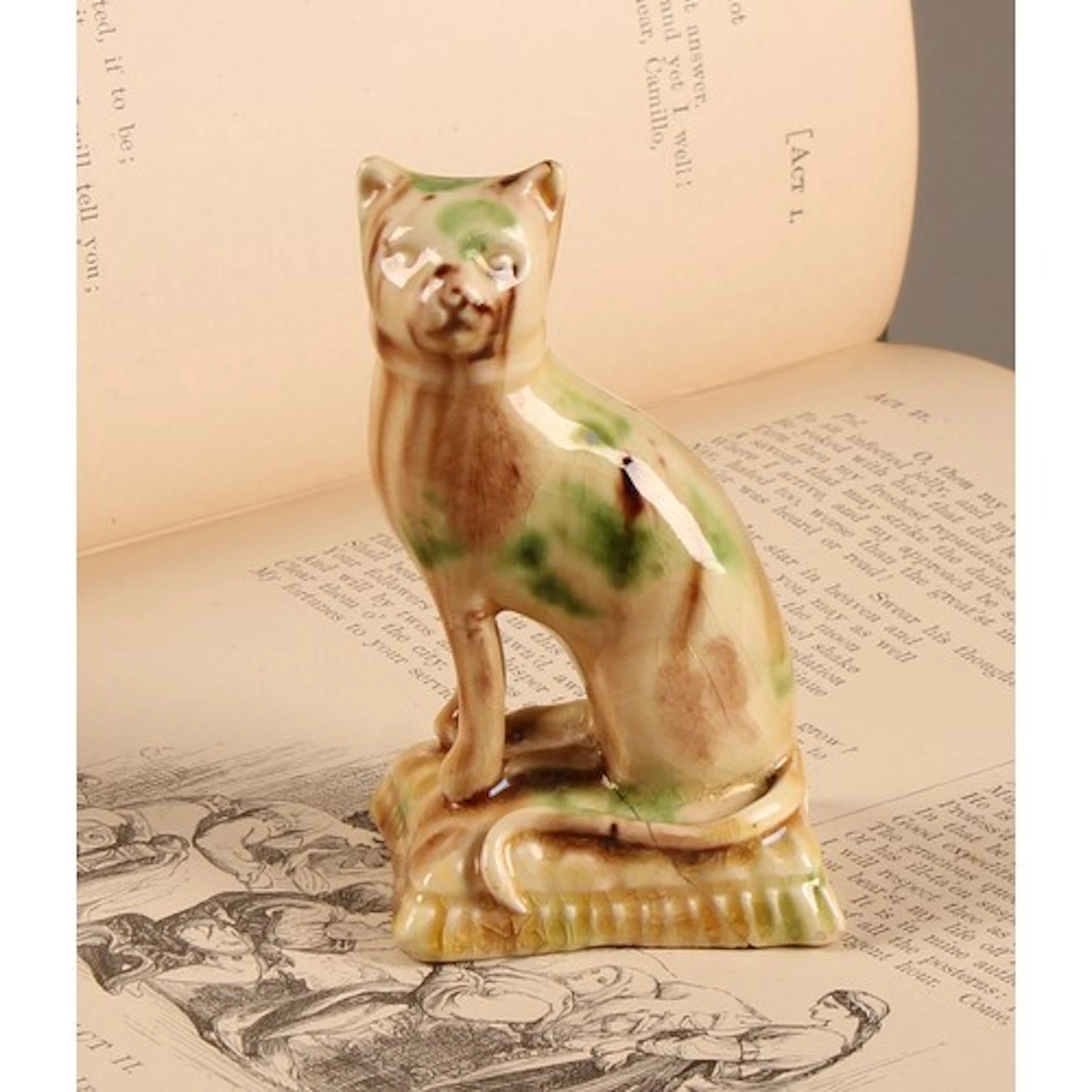 A creamware model of a cat, seated on a cushion, glazed in t...