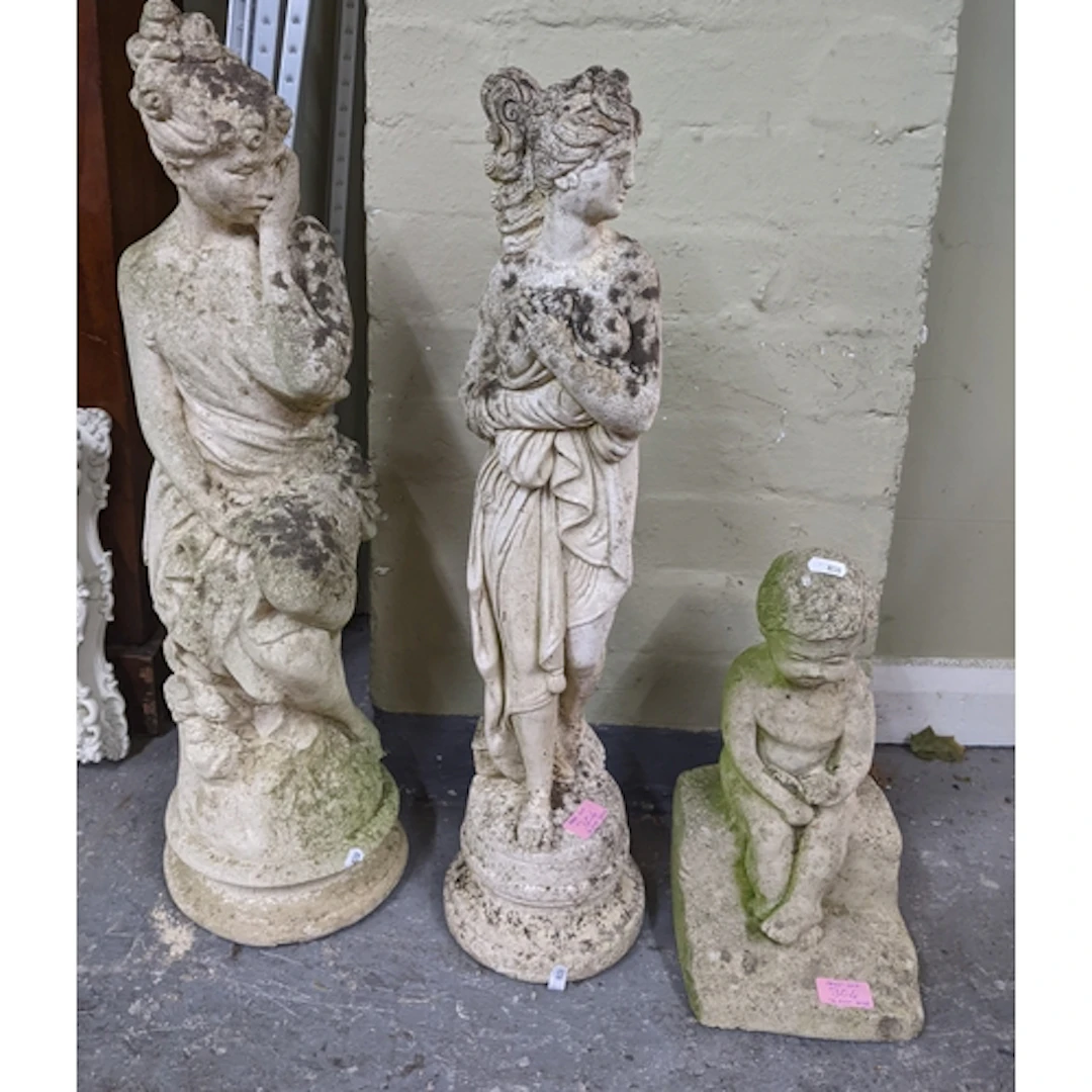 A group of three weathered concrete garden statues, tallest ...