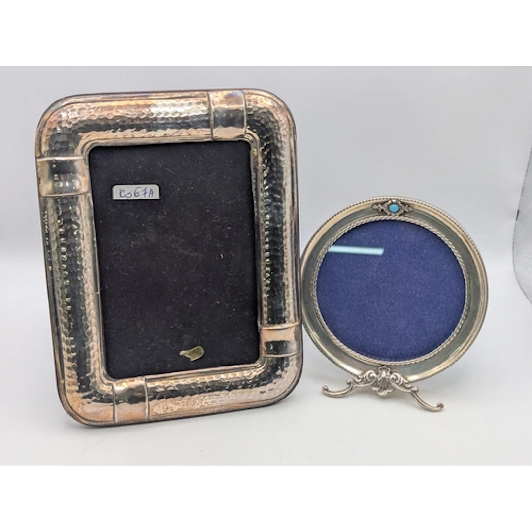 Two silver fronted easel back photograph frames, one in circ...