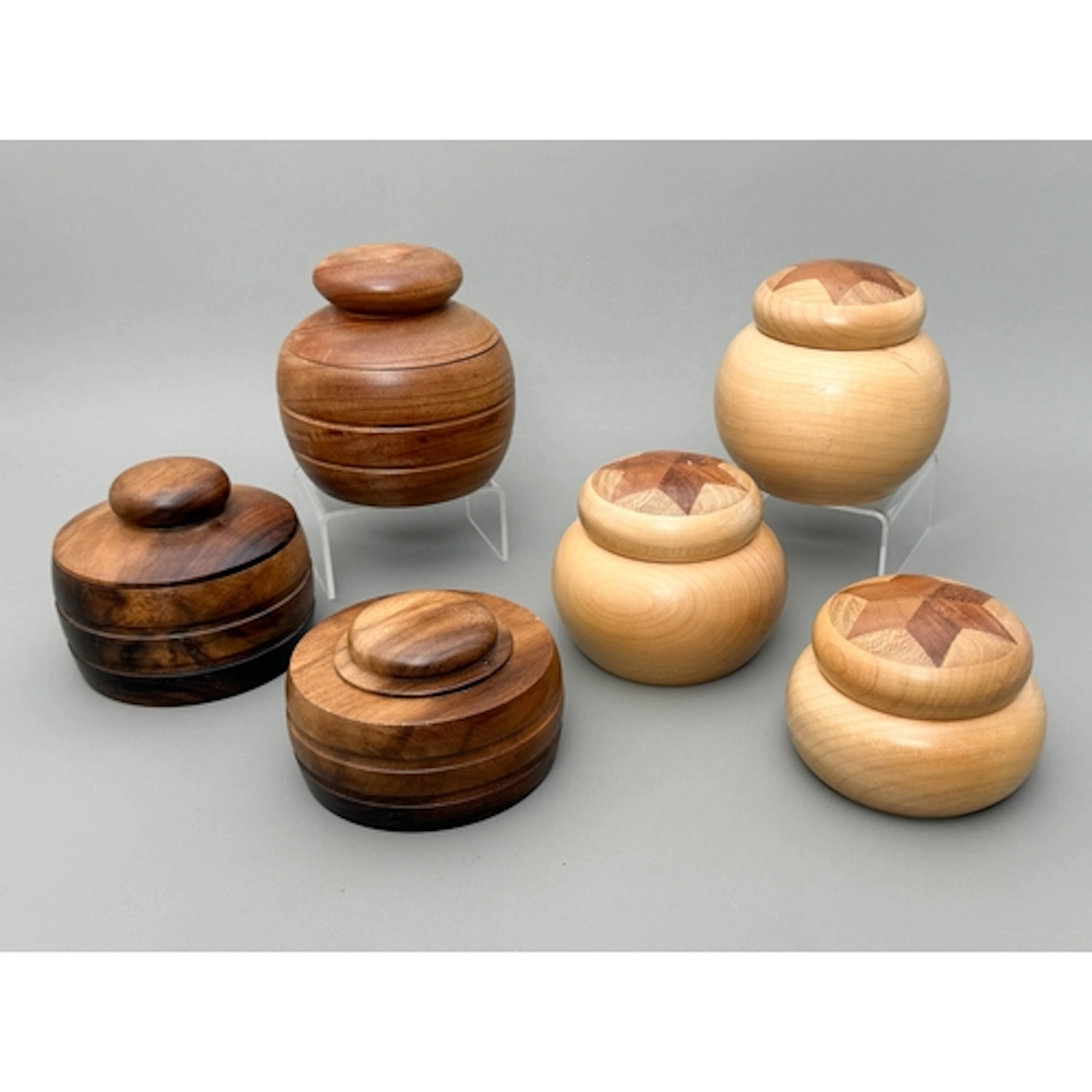 A group of six turned wooden lidded pots - to include a grad...