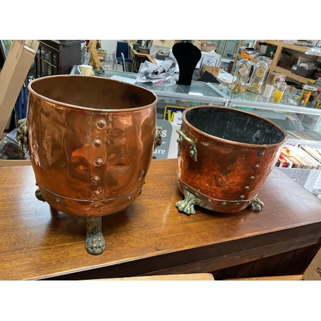 Two copper and brass scuttles on lion claw feet.