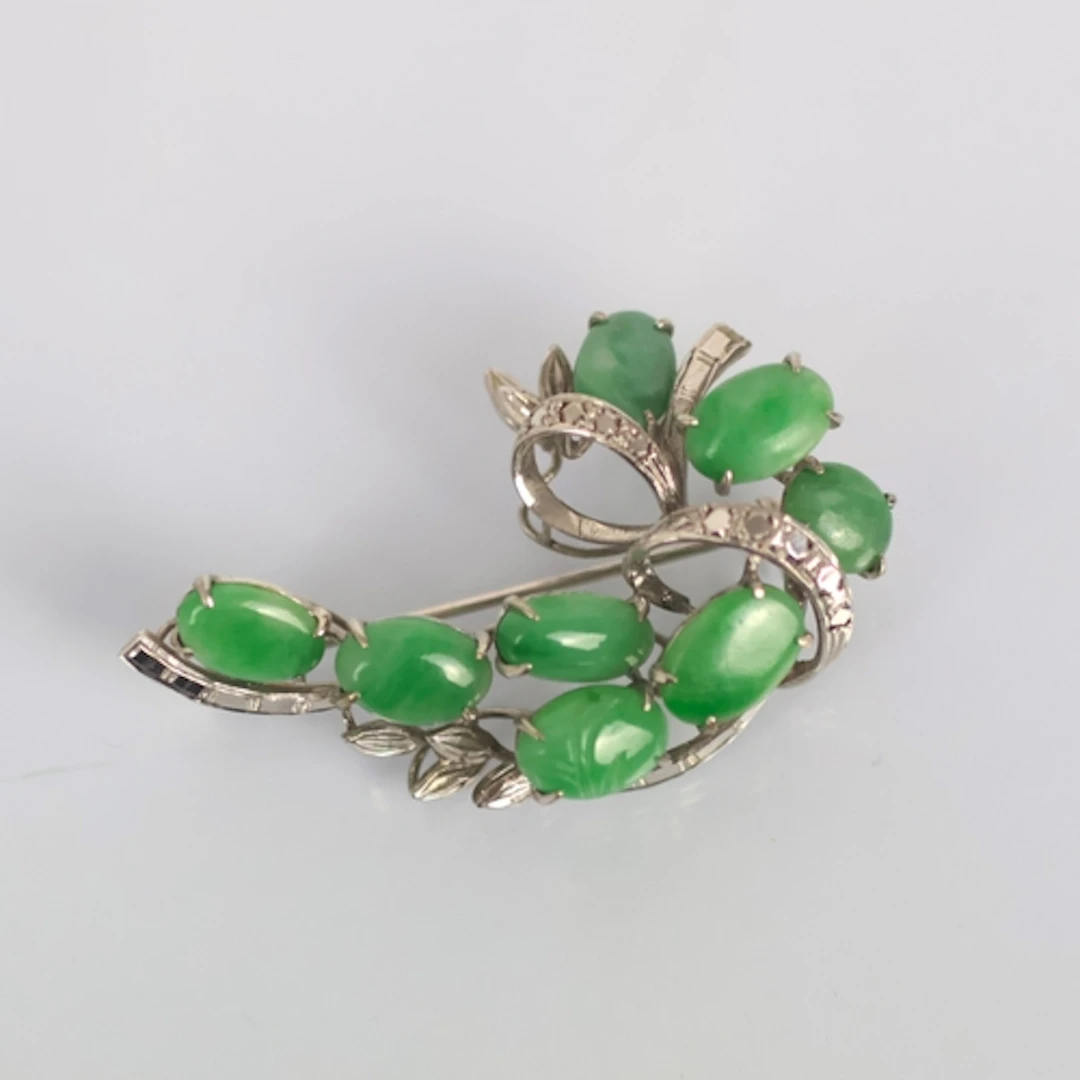 A continental 'jadeite' white metal brooch, of stylised spra...