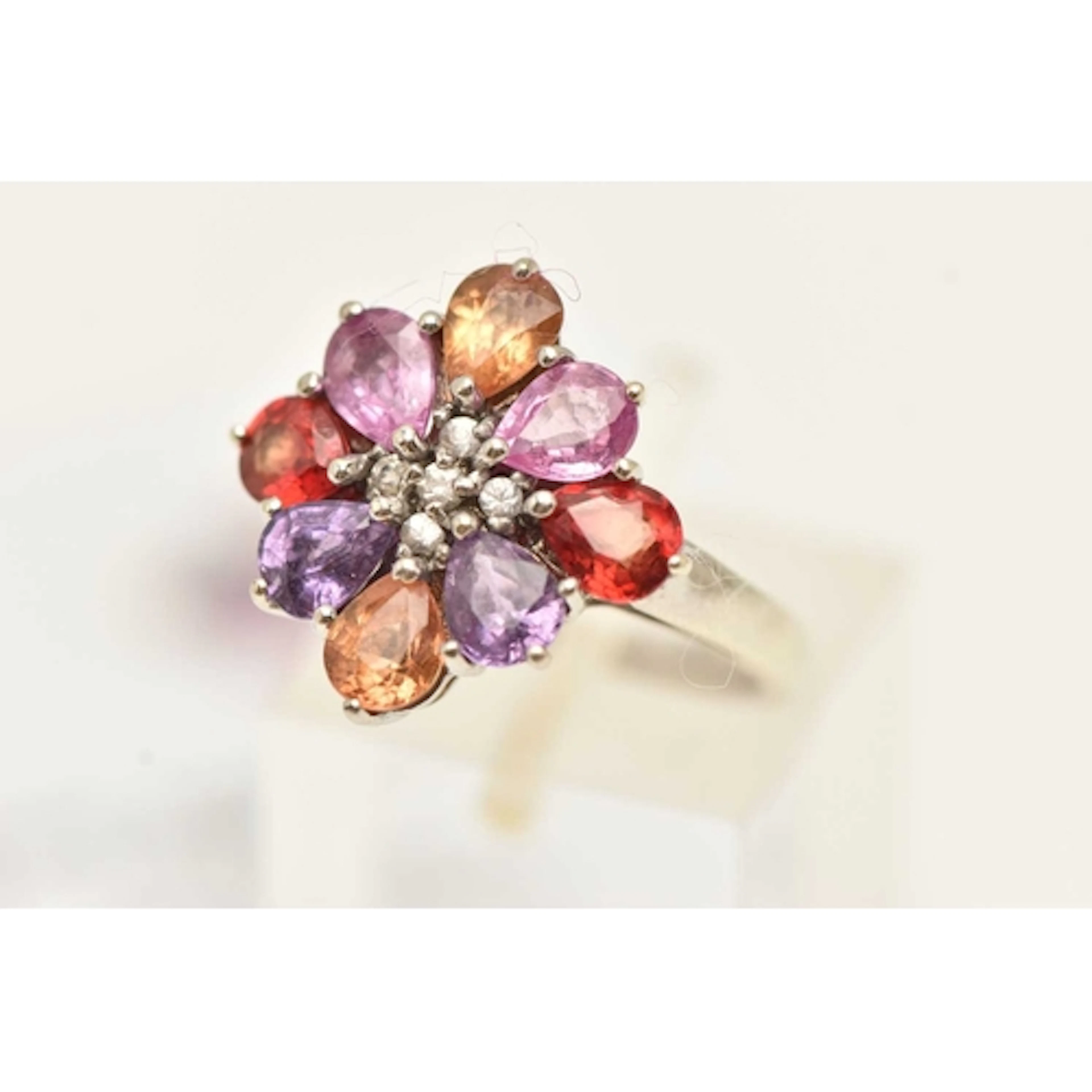 A 9CT WHITE GOLD GEM SET RING, a floral cluster set with pin...
