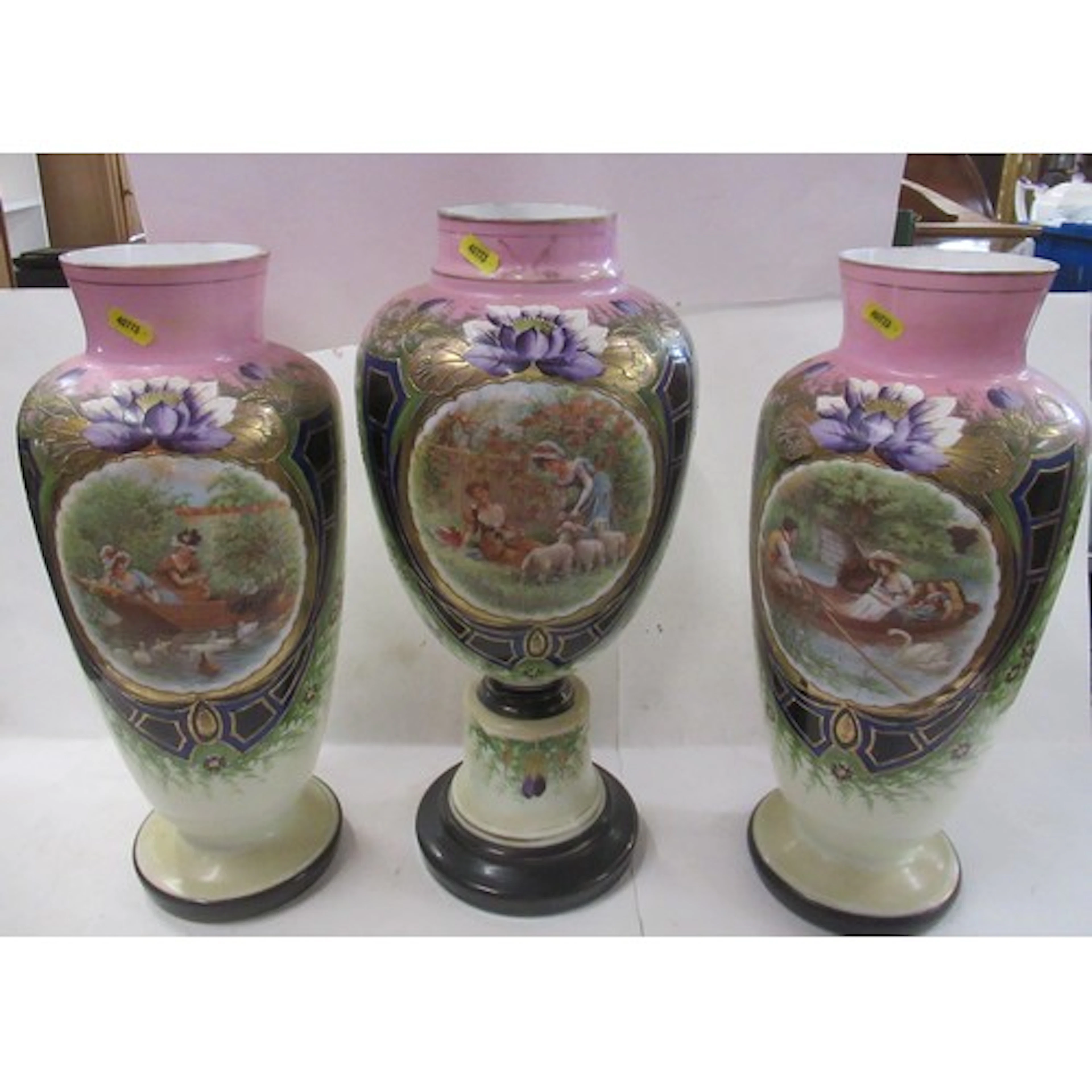 A Victorian garniture of glass vases, decorated with reserve...