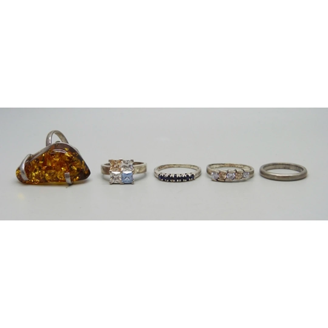 Five silver and white metal rings, one a/f faux amber requir...