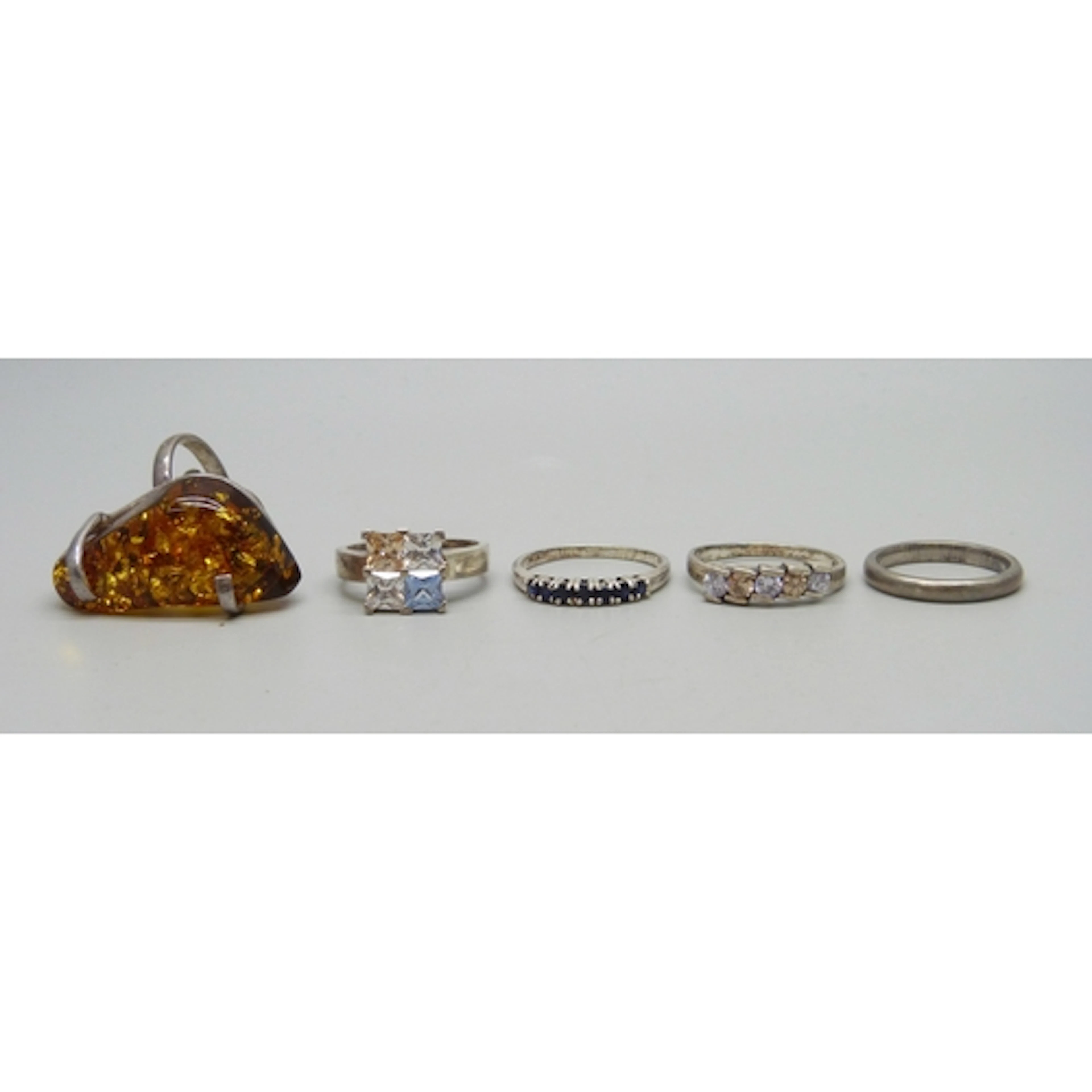 Five silver and white metal rings, one a/f faux amber requir...