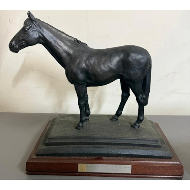 Racing interest. A bronze sculpture of a horse on wooden pli...