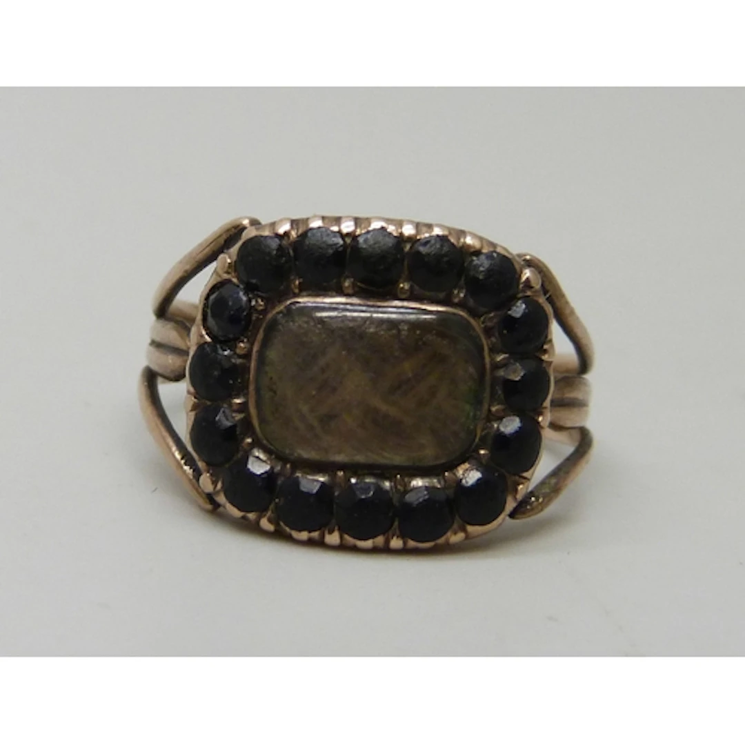 A George III yellow metal mourning ring with hairwork panel,...