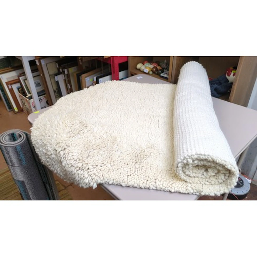 Cream wool rug with a deep, densely looped pile and a flat-w...