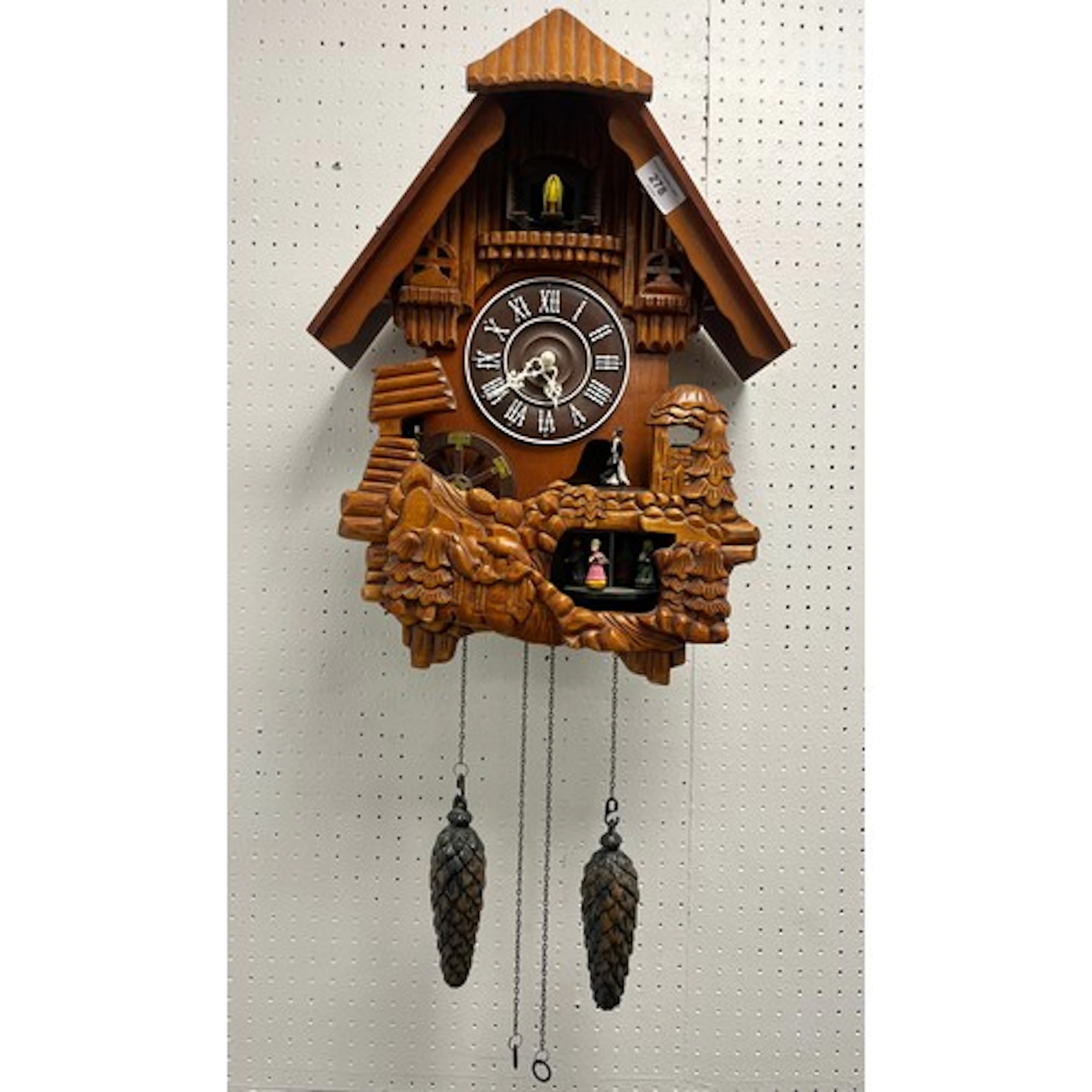 Modern cuckoo clock with carousal and pine cone weights.