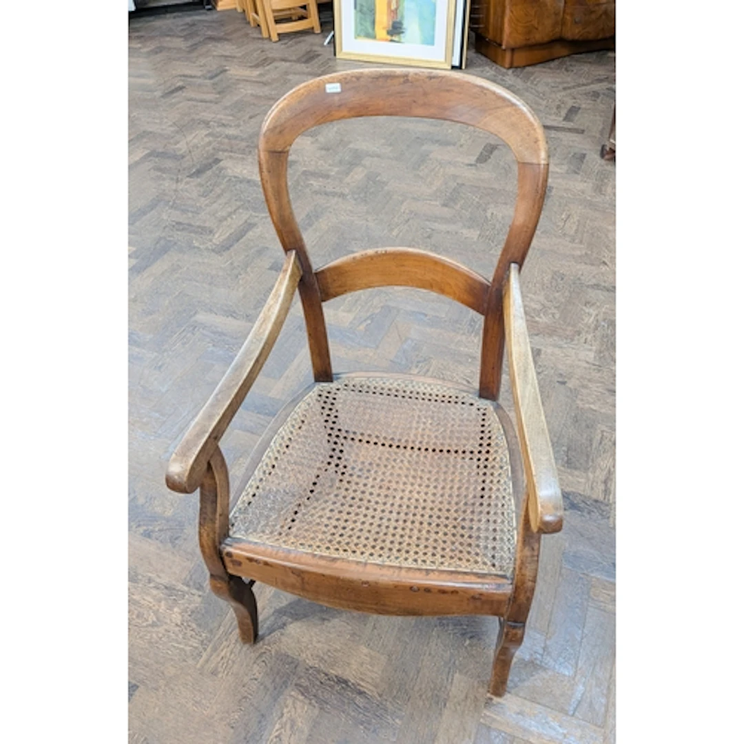 A mahogany balloon back elbow chair with cane panel seat