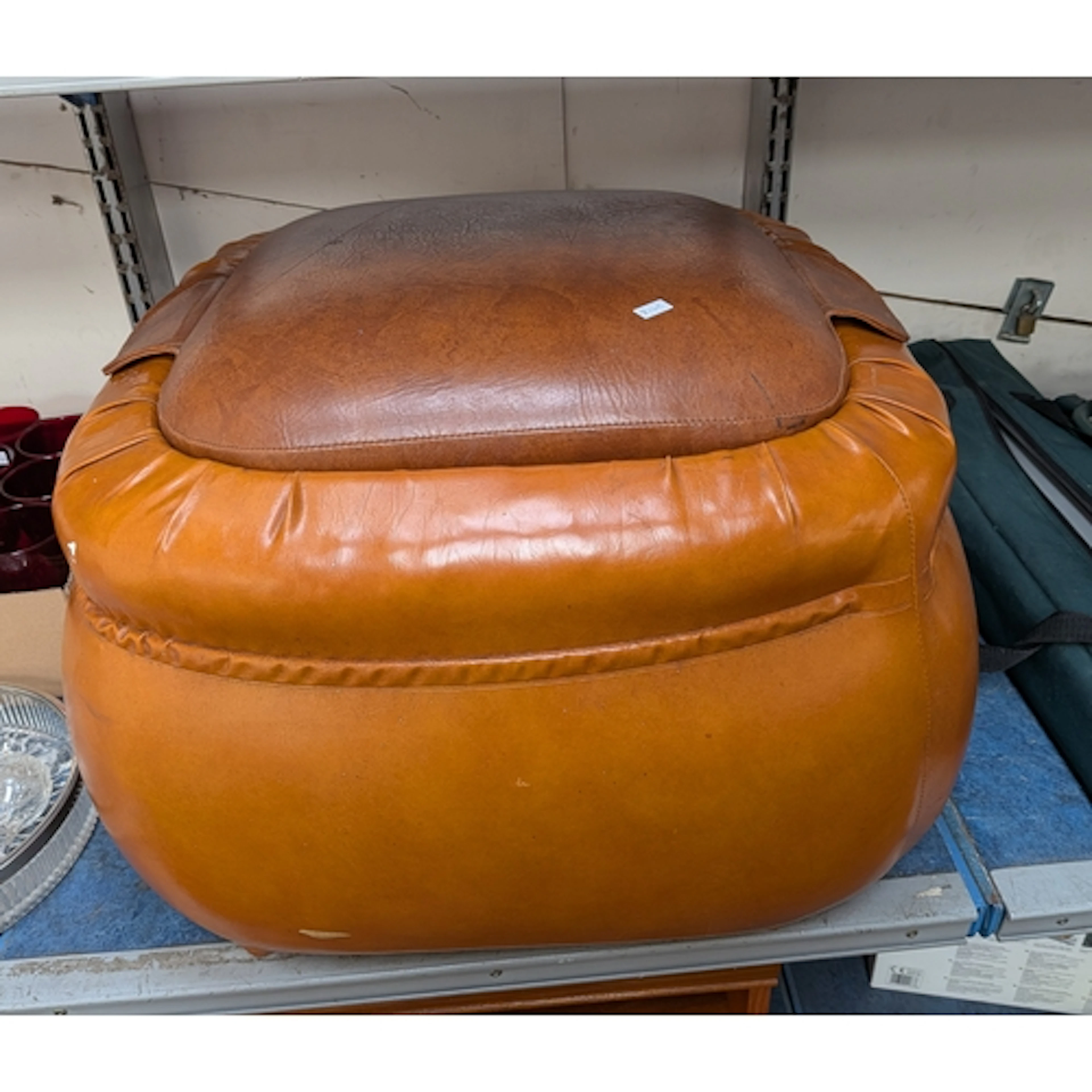 A large brown leather footstool or storage ottoman