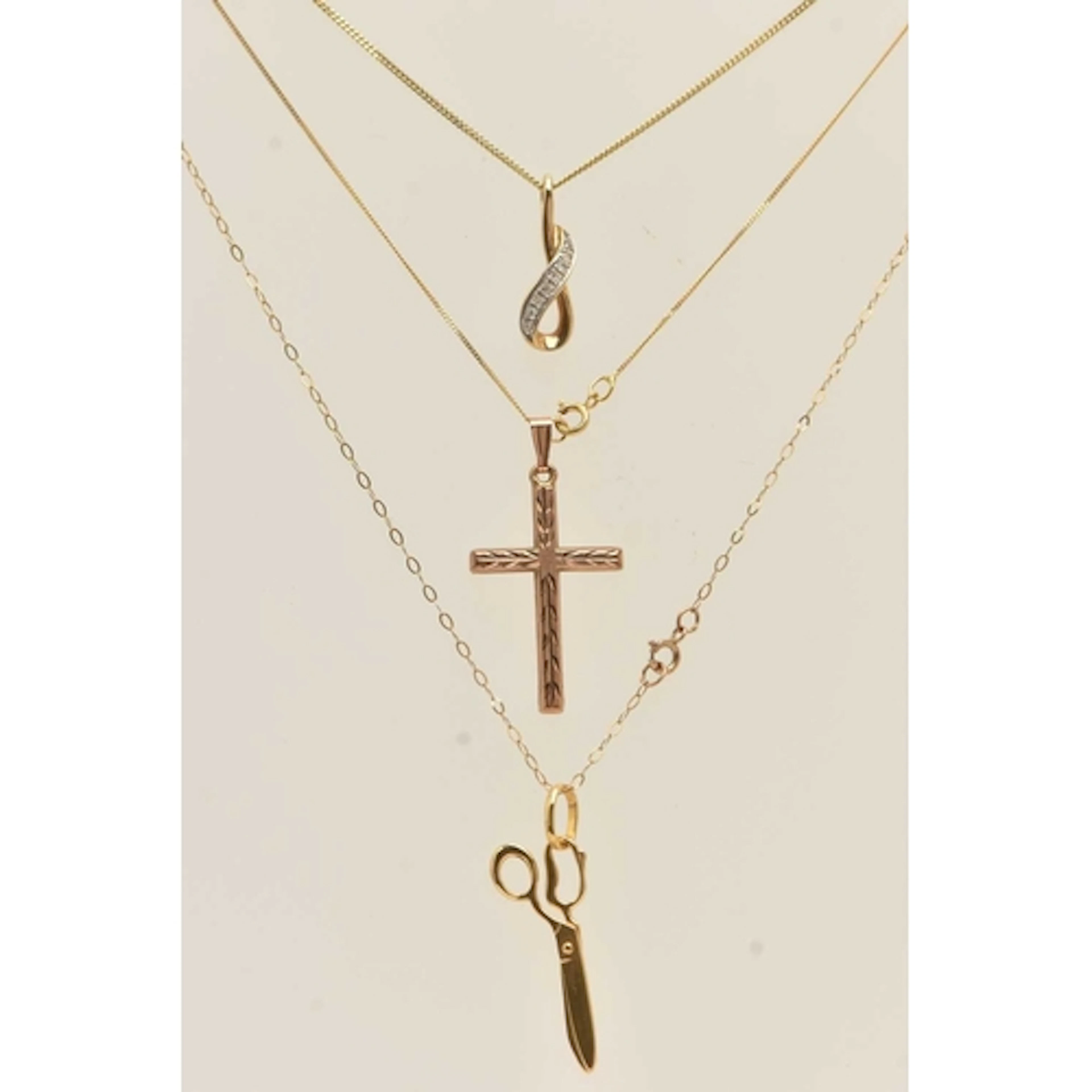 THREE PENDANT NECKLACES, the first a 9ct yellow gold diamond...