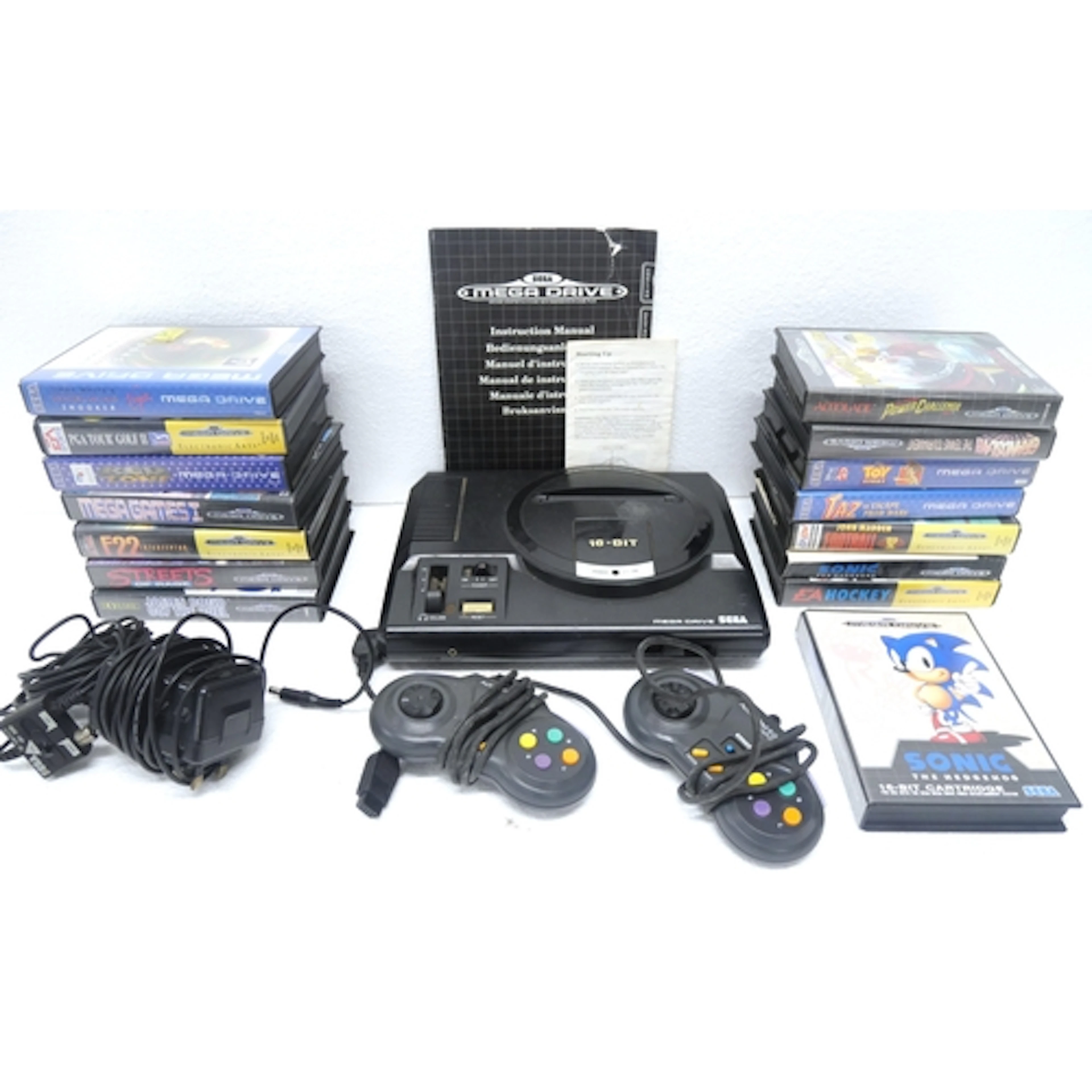 A Sega Mega Drive 16-bit games console with power supply, tw...