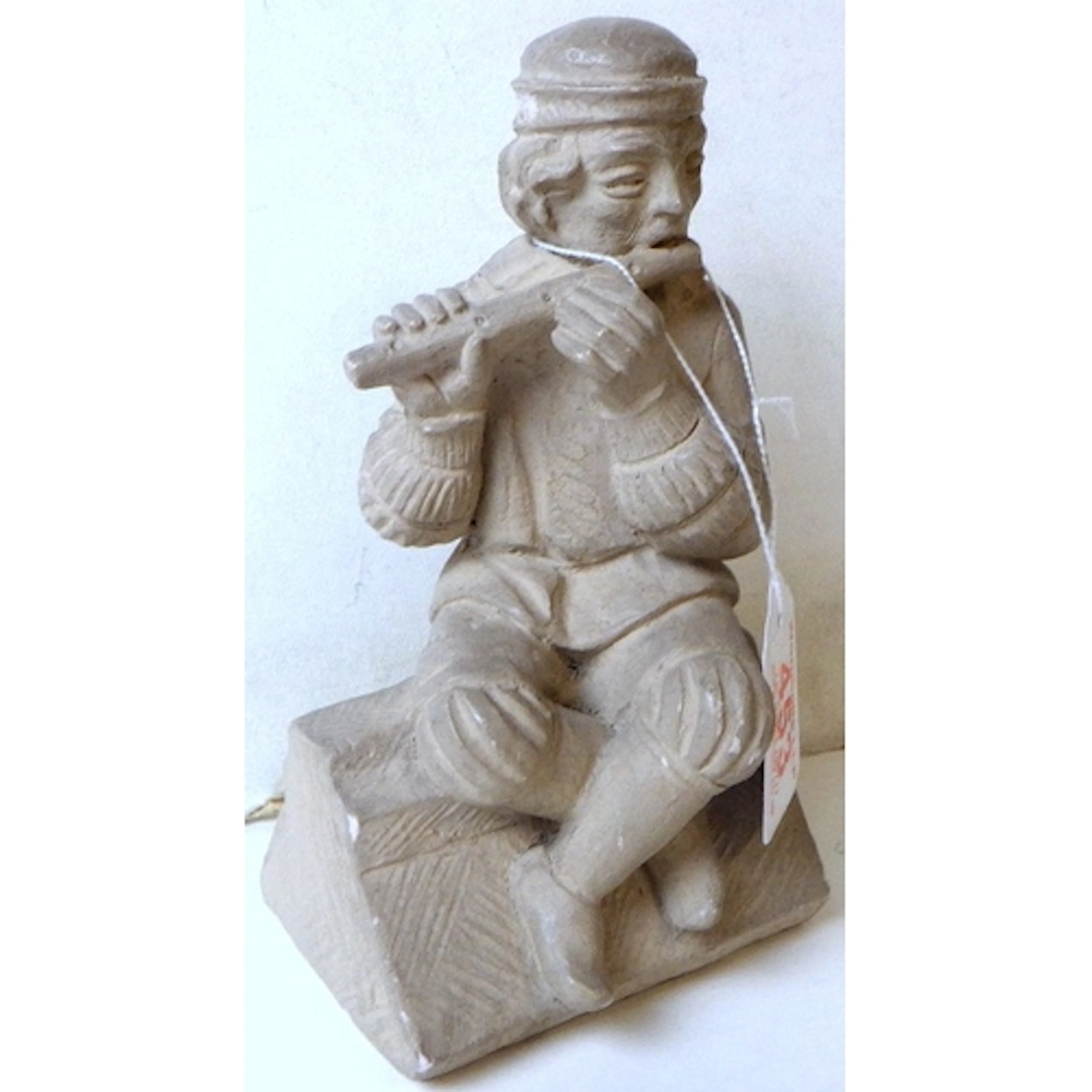A medieval fifer sat on a stone moulding, grey clay maquette...