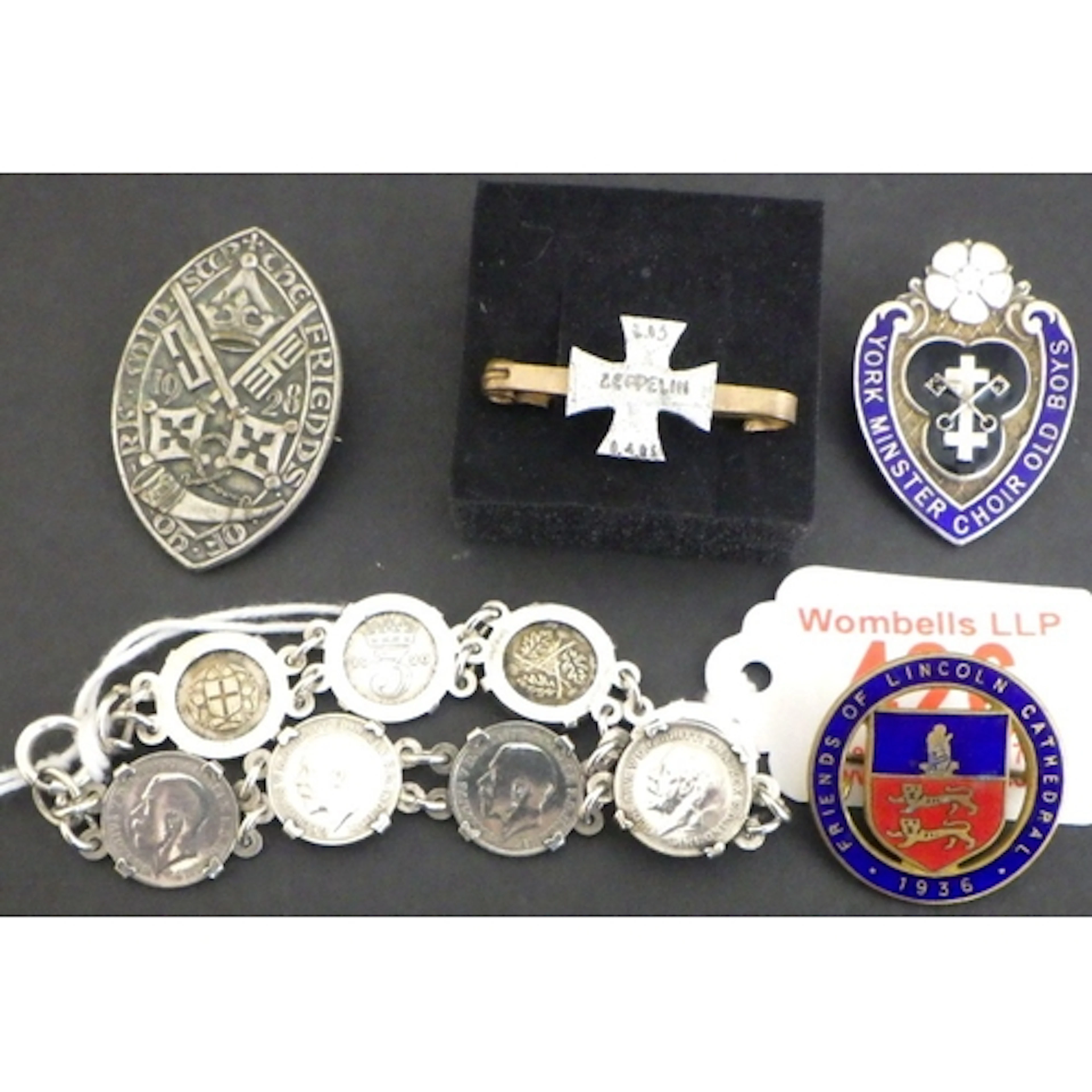 A silver coin bracelet, badges and a Zepplin broach (materia...