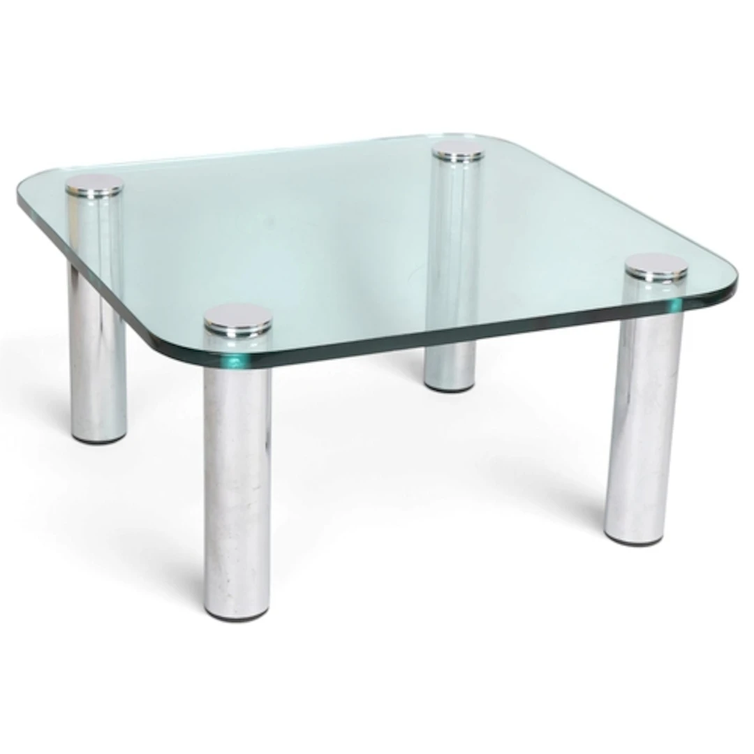 A mid century glass top coffee table on chrome legs in the m...