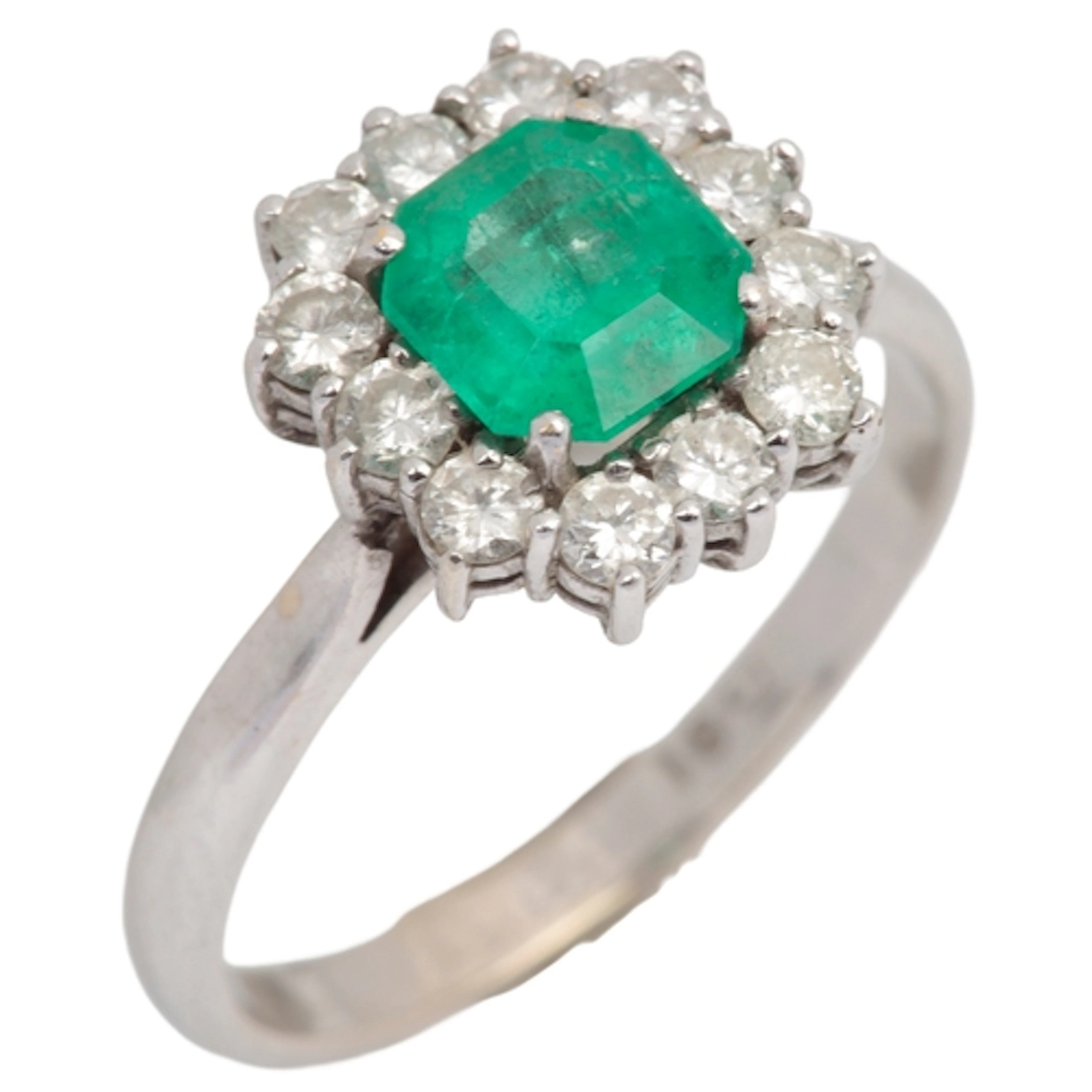 An emerald and diamond ring, of cluster design, claw-set wit...