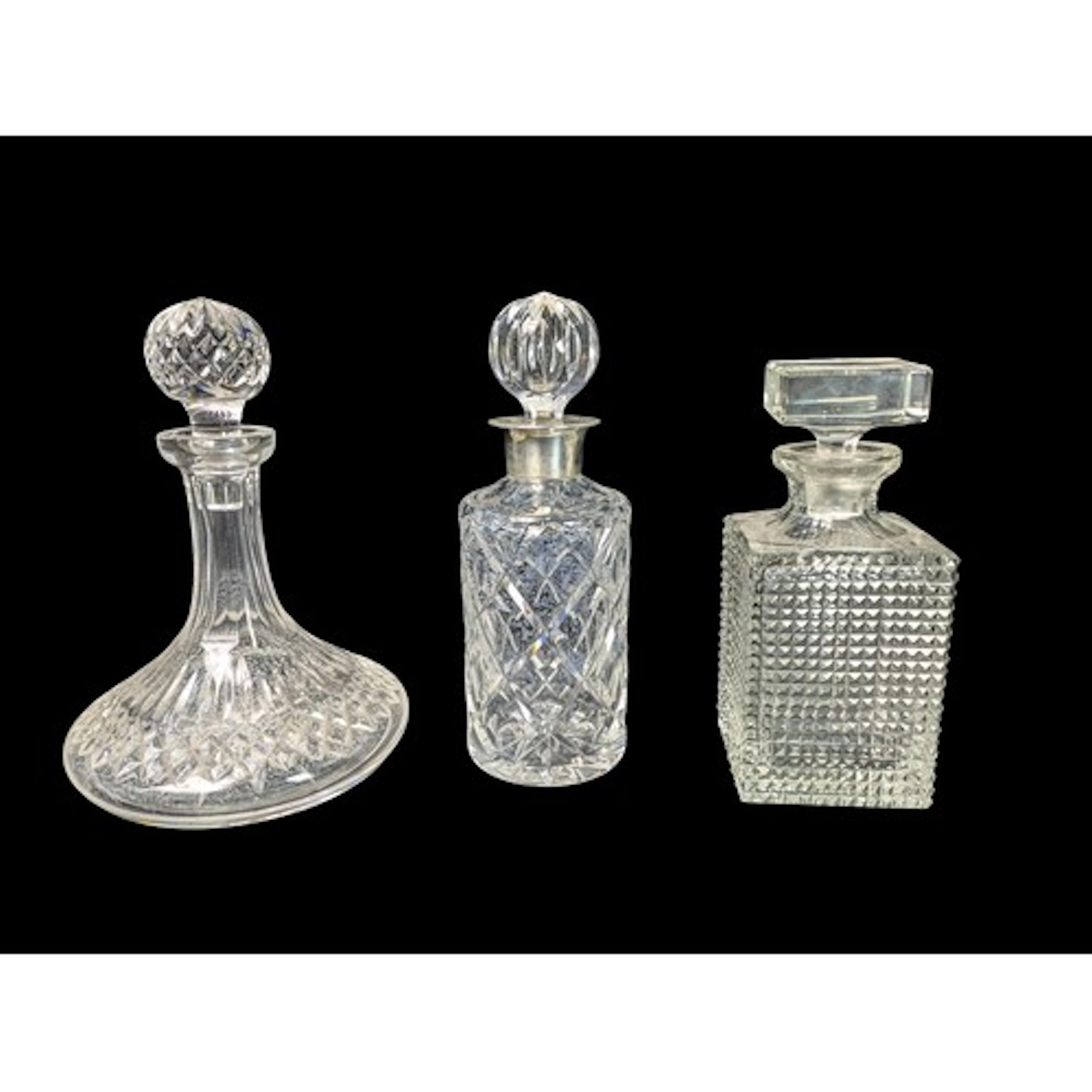 Three cut-glass decanters: a cylindrical example with a hall...
