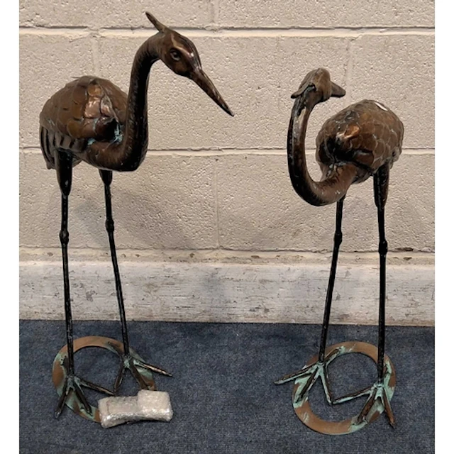 TWO COPPERIZED METAL CRANES, one facing backwards, raised on...