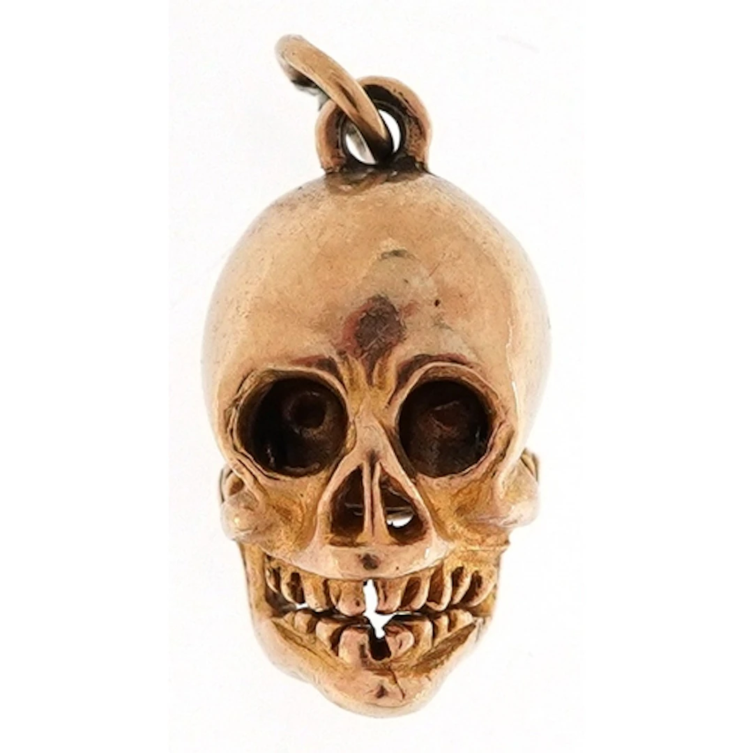 9ct gold charm in the form of a human skull with hinged jaw,...
