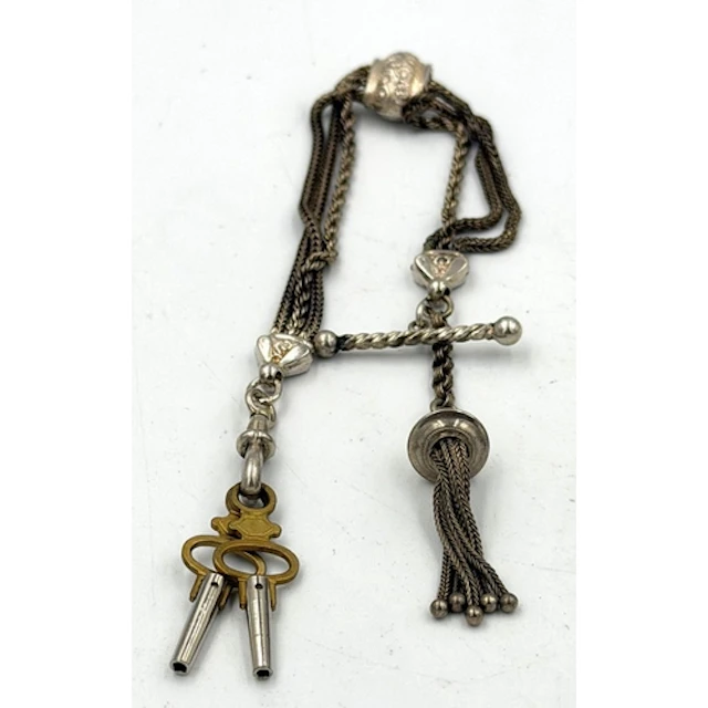 An ornate white metal pocket watch chain.
