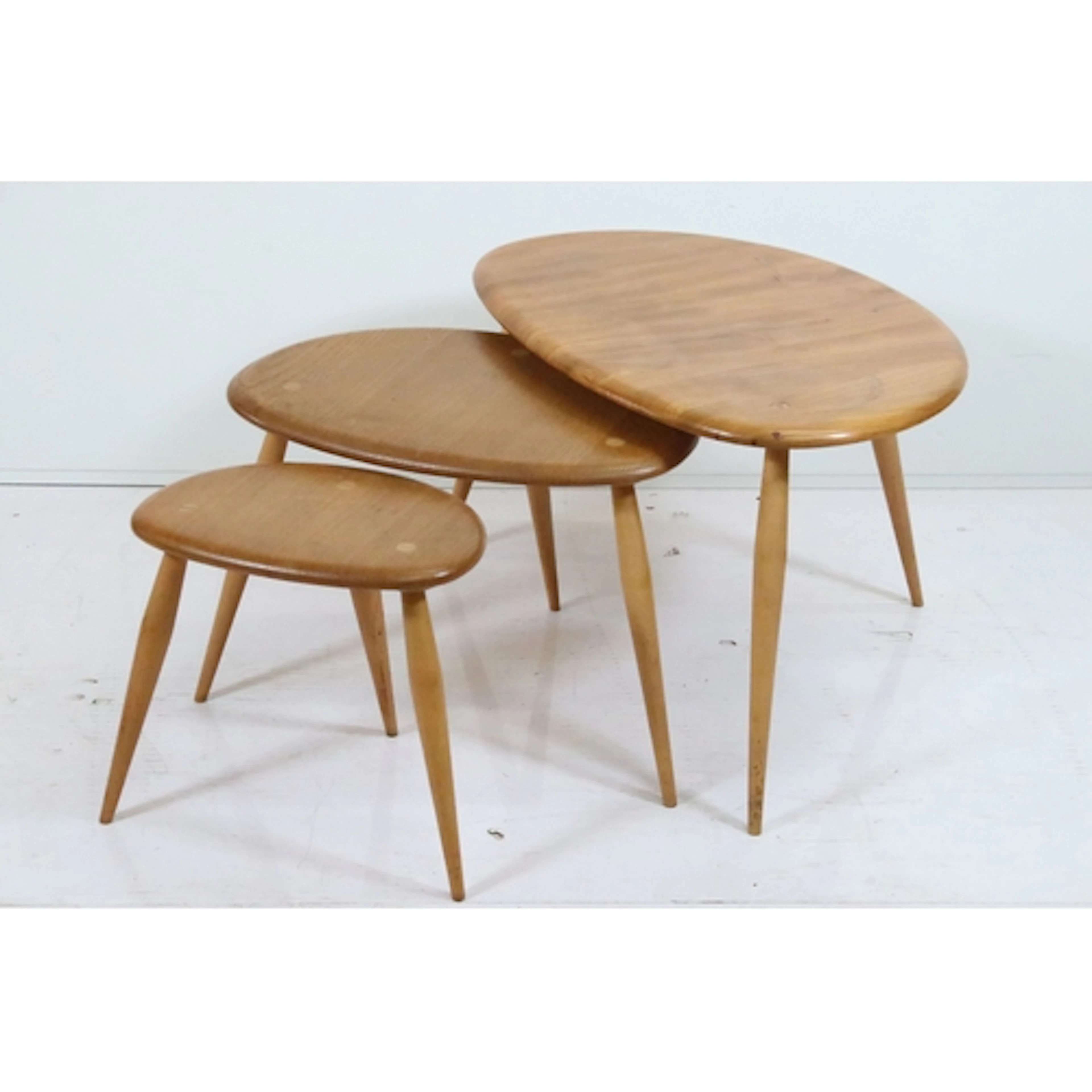 Ercol blonde elm 'Pebble' nest of three tables, each one rai...