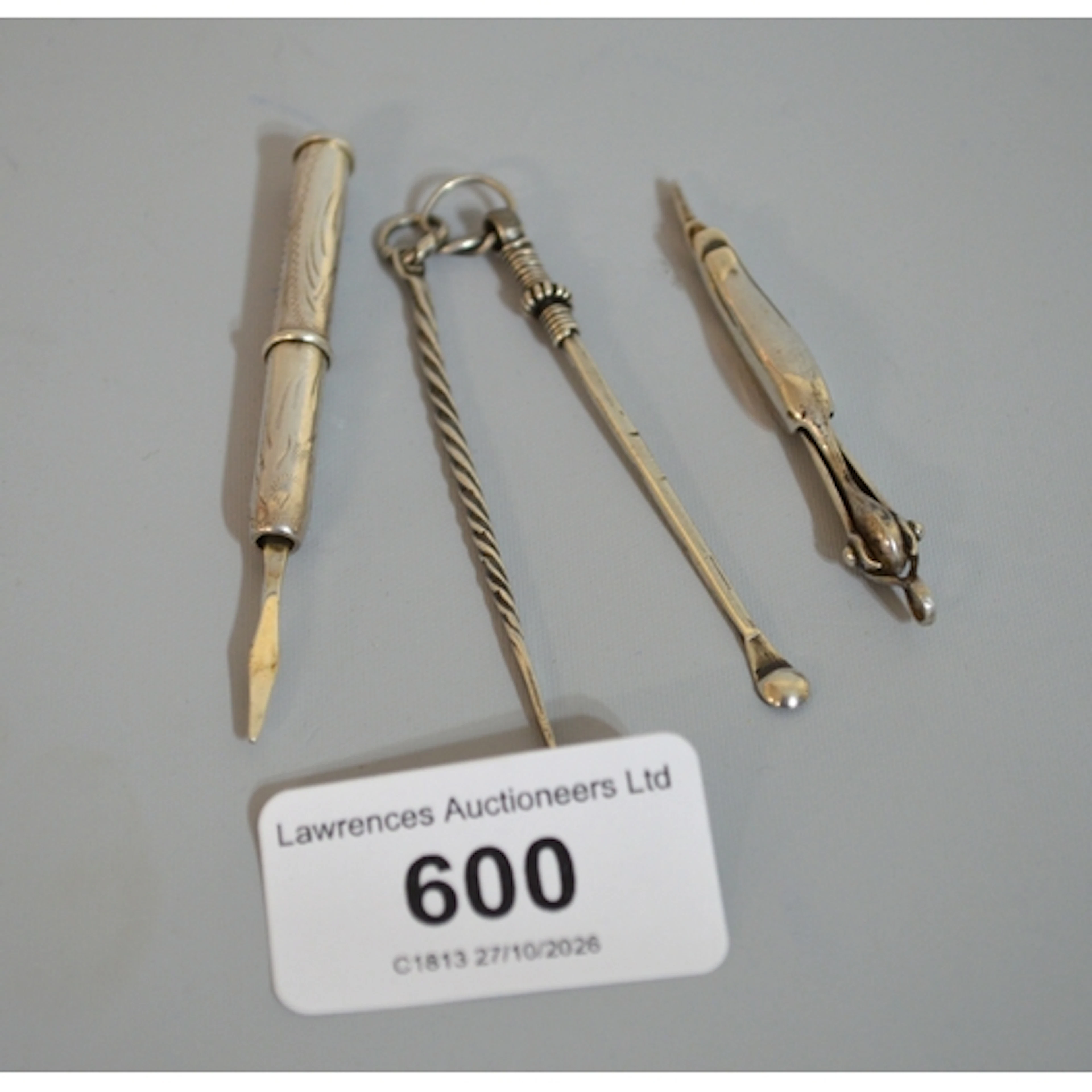 Group of three silver toothpicks and an earwax remover