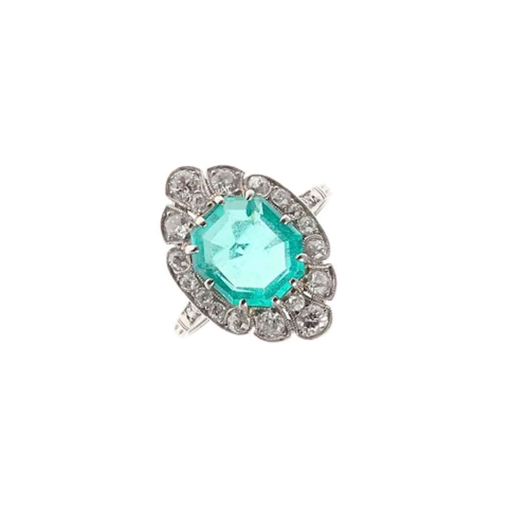AN EMERALD AND DIAMOND CLUSTER RING. the octagonal-shaped em...