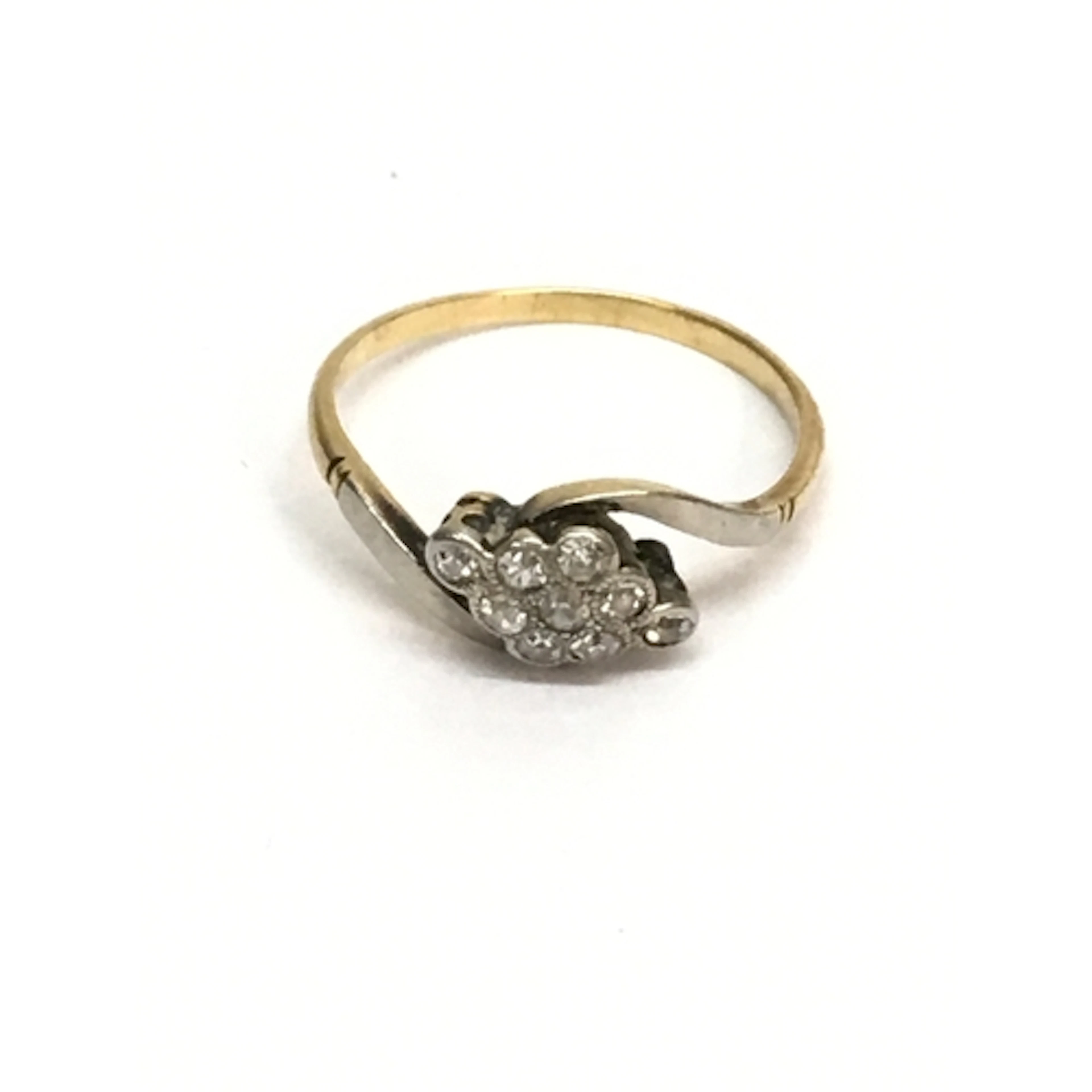 An unmarked gold ring set with white stones in twist setting...