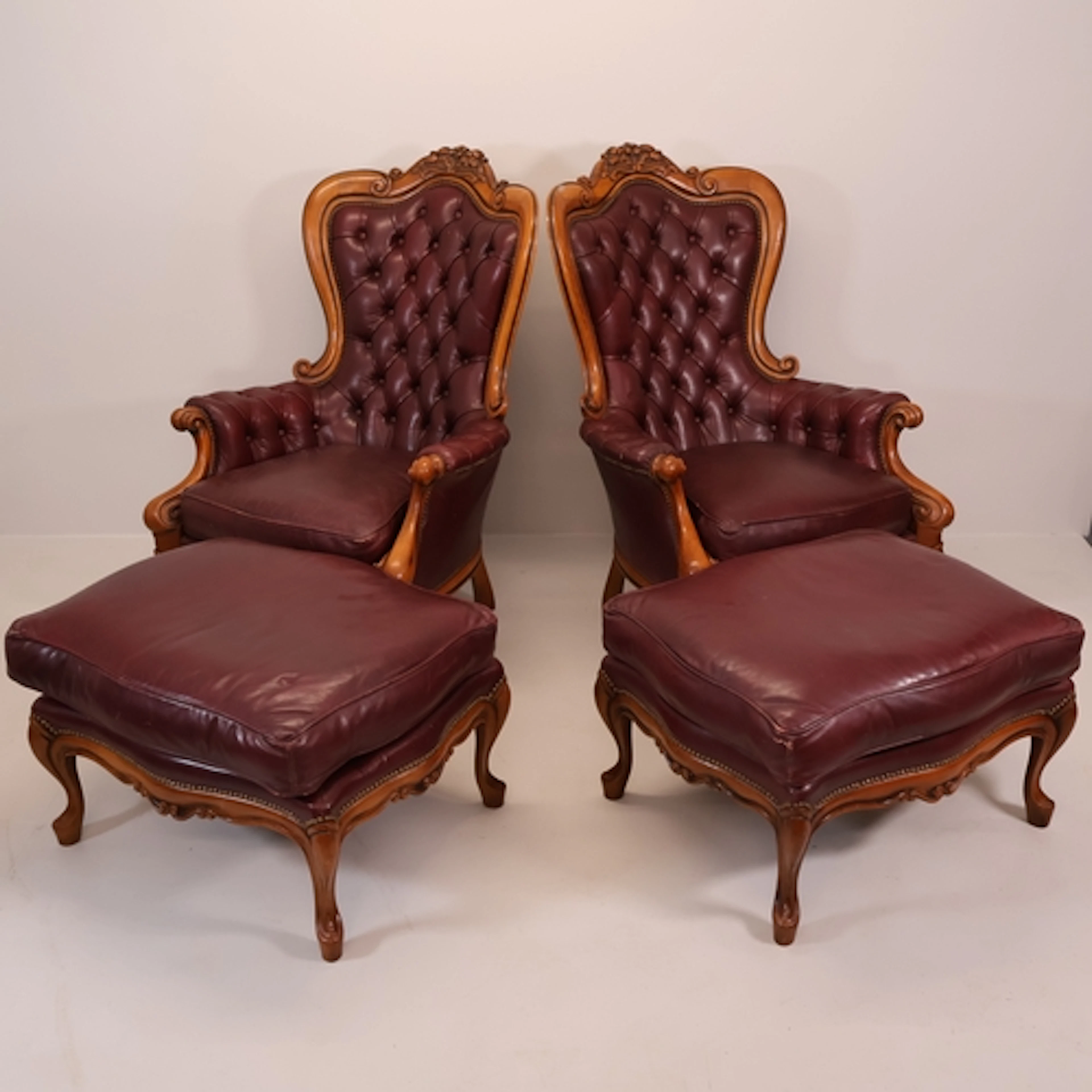 A pair of French Rococo style walnut and button-back leather...