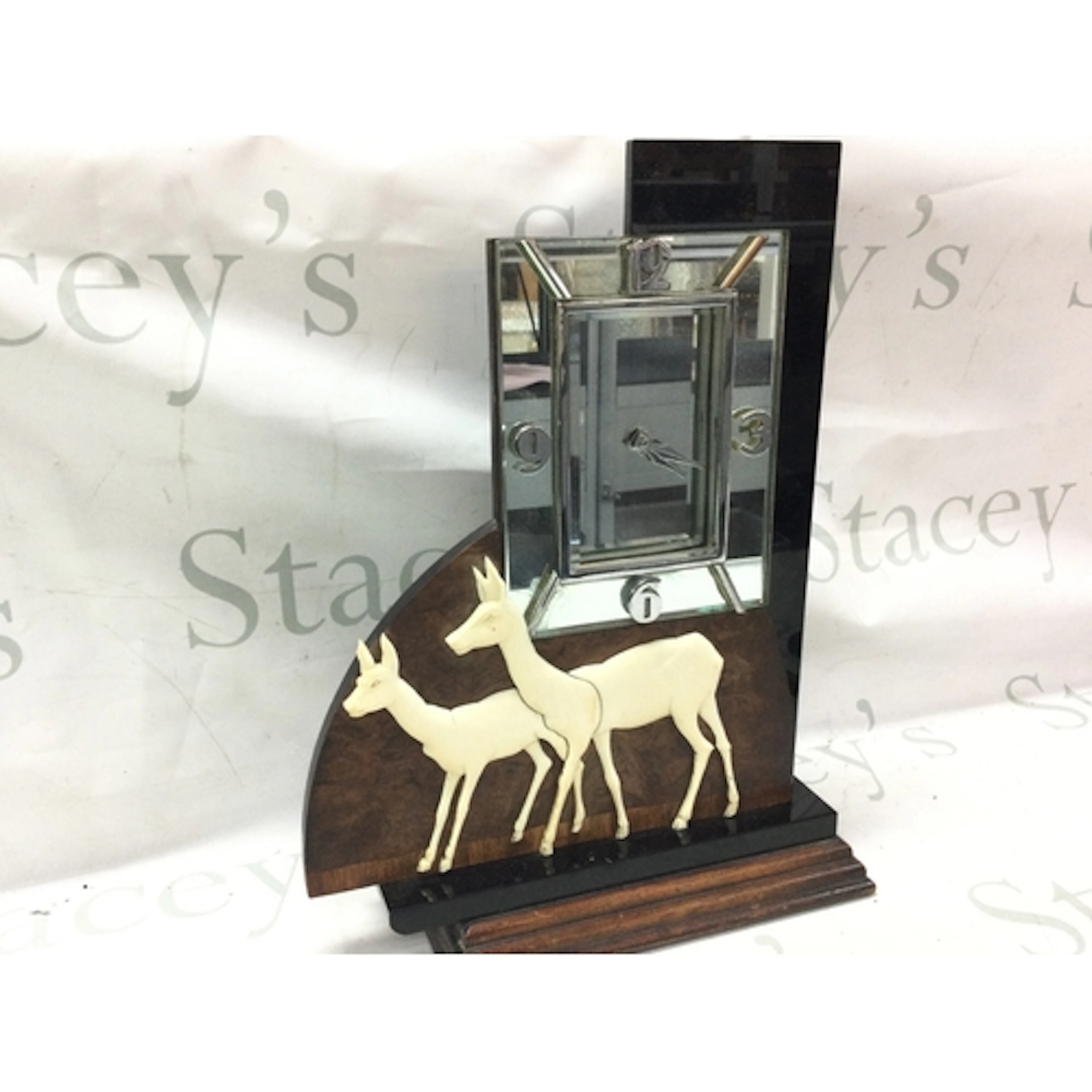An Art Deco electric mantle clock featuring a pair of deer a...