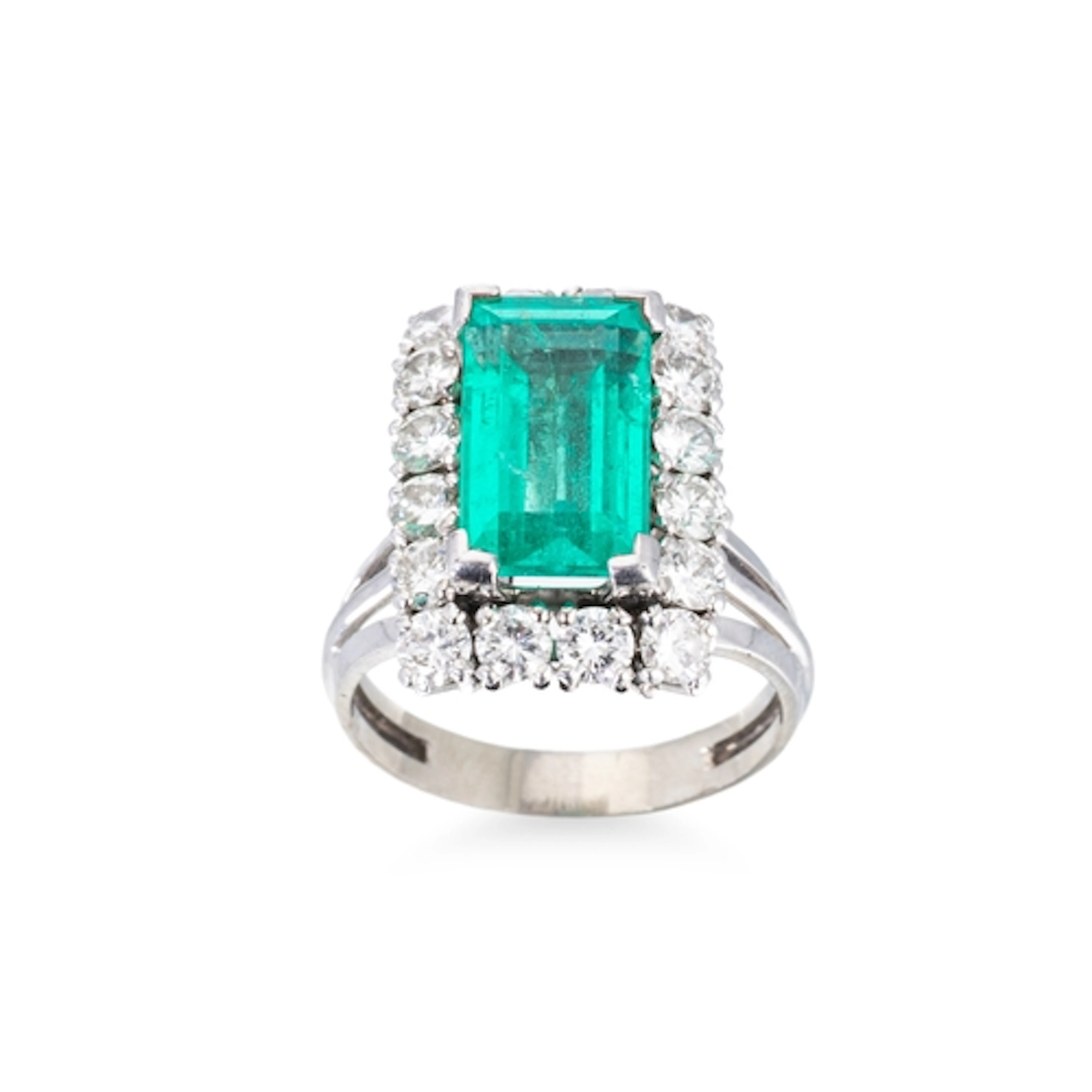 AN EMERALD AND DIAMOND CLUSTER RING, the emerald cut emerald...
